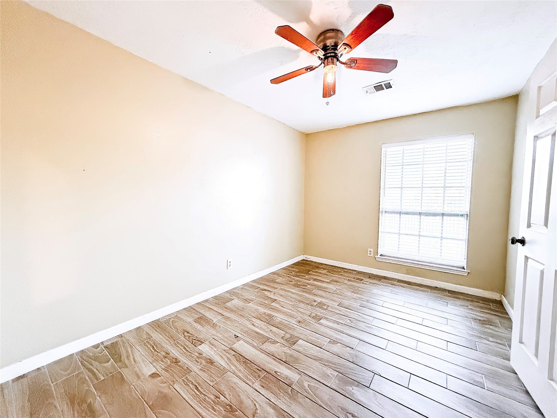 8116 Gulick Lane, Houston, TX 77075 Bright and inviting room featuring wood-look tile flooring, a ceiling fan, and a large window that allows natural light to fill the space.
