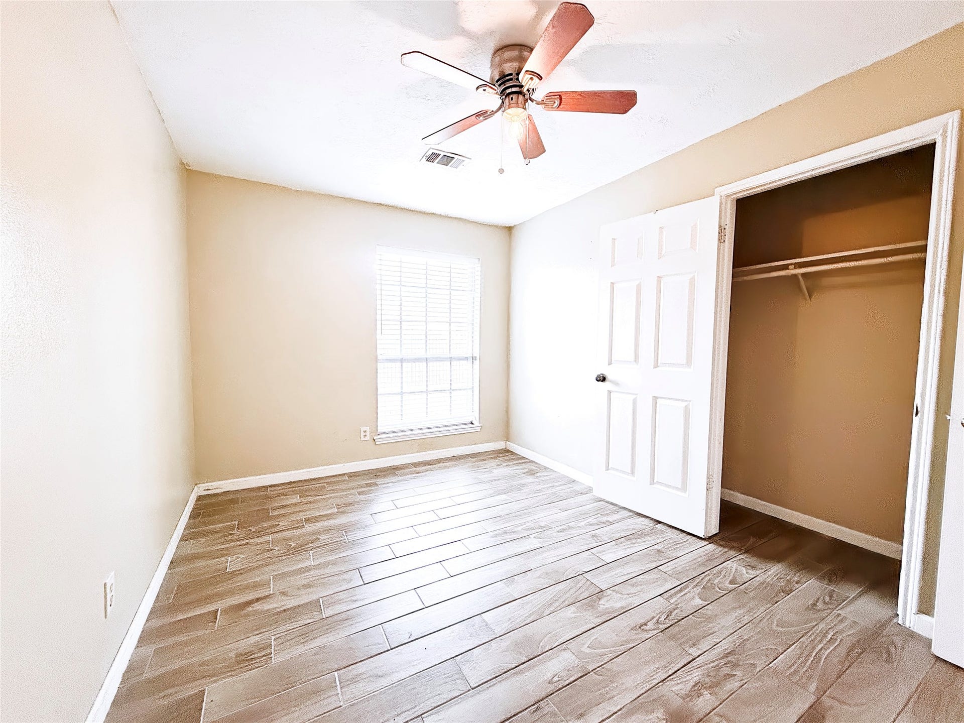 8116 Gulick Lane, Houston, TX 77075 Bright and inviting bedroom featuring wood-look tile flooring, a ceiling fan, and ample natural light from a large window, complete with a spacious closet.