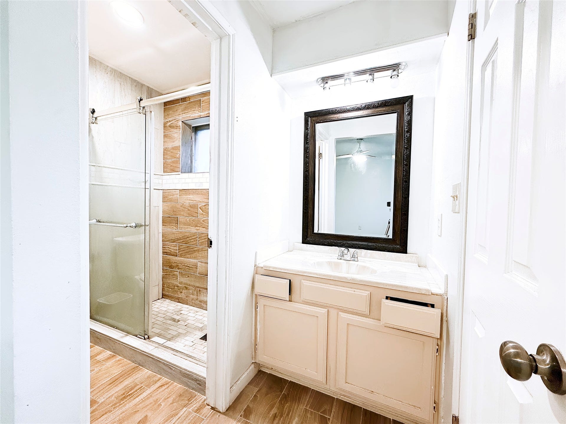 8116 Gulick Lane, Houston, TX 77075 Charming bathroom featuring a sleek glass-enclosed shower with elegant tilework, complemented by a spacious vanity with a large framed mirror.