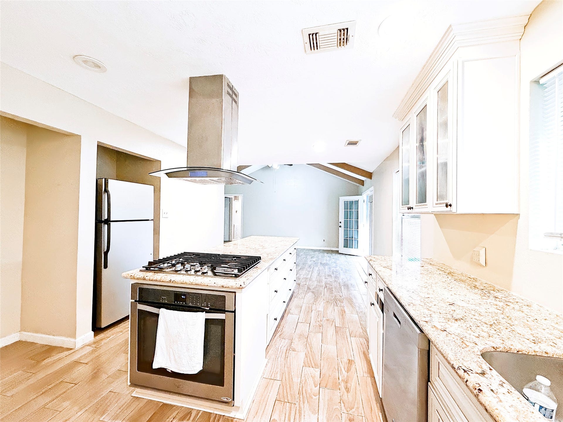 8116 Gulick Lane, Houston, TX 77075 A spacious kitchen featuring modern stainless steel appliances, a sleek range hood, and granite countertops, complemented by ample natural light and elegant cabinetry.