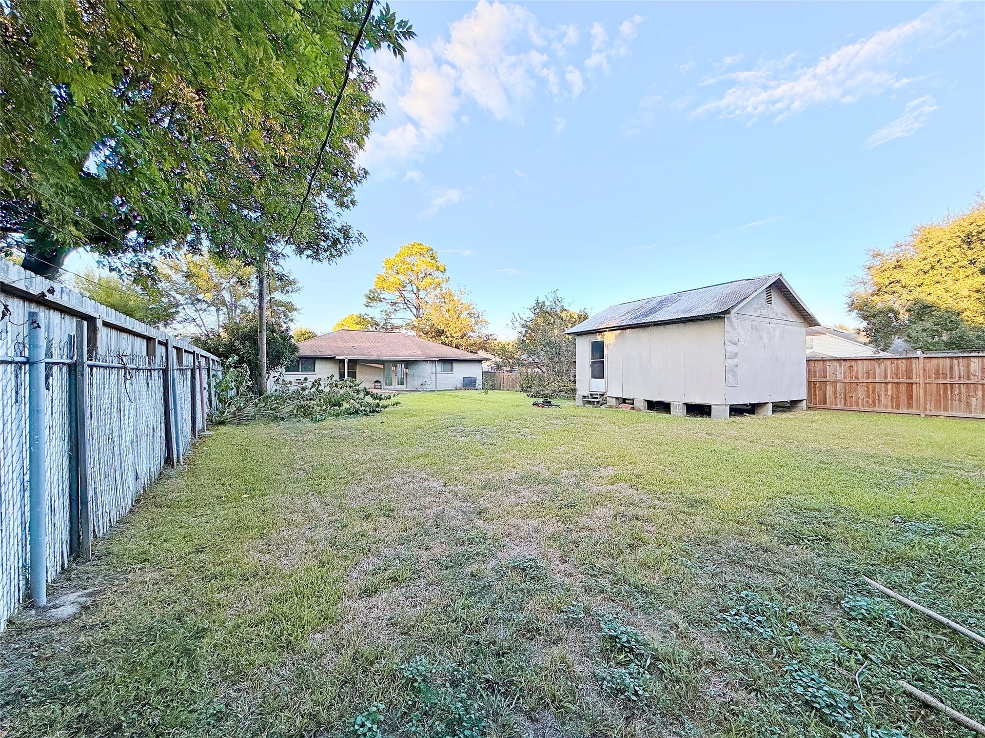 8116 Gulick Lane, Houston, TX 77075 Expansive backyard featuring a spacious lawn, a detached storage shed, and mature trees offering ample shade and privacy.