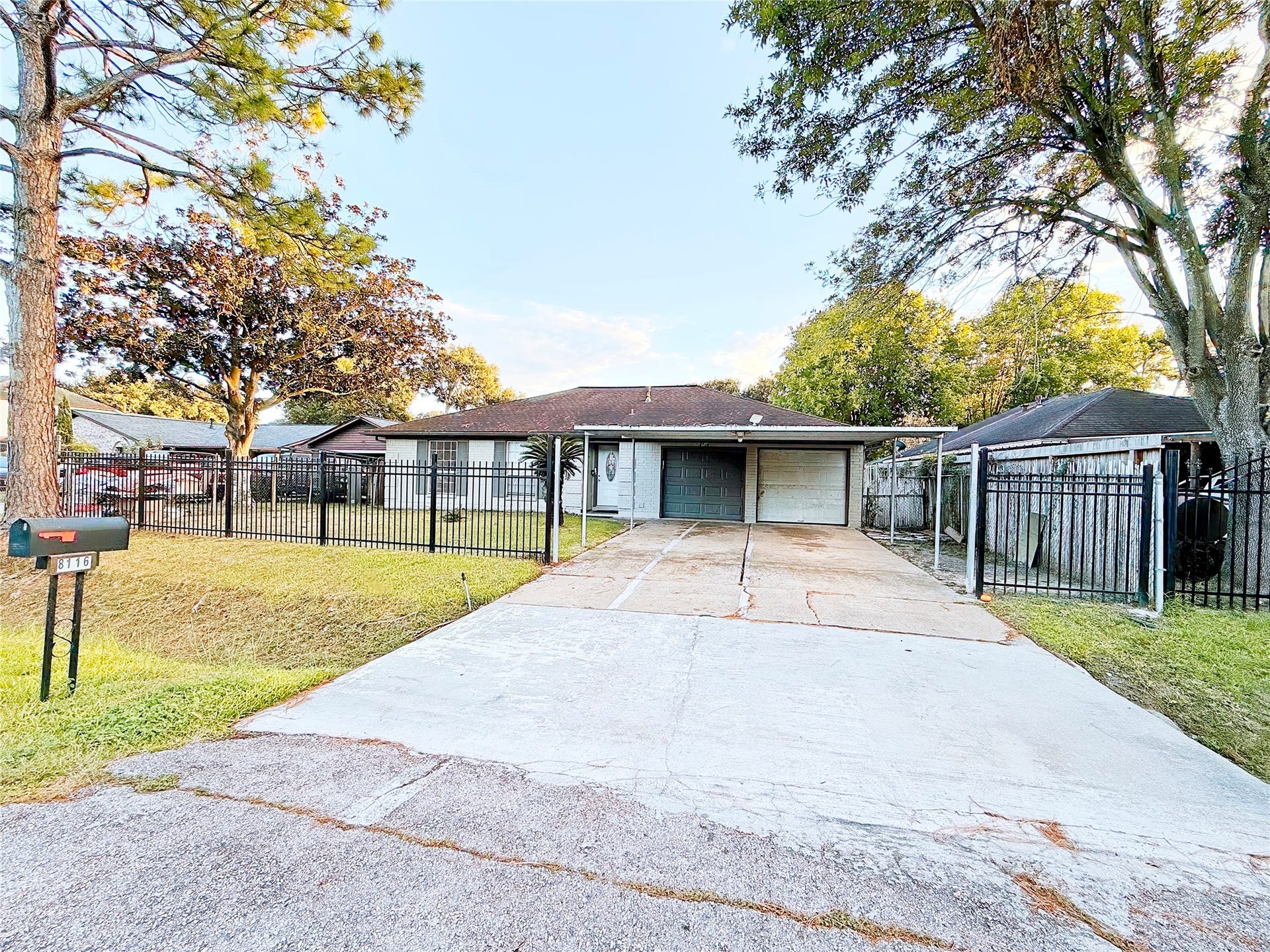 8116 Gulick Lane, Houston, TX 77075 Charming ranch-style home with a spacious driveway and a secure, gated front yard. Surrounded by mature trees, it offers a serene and private setting.