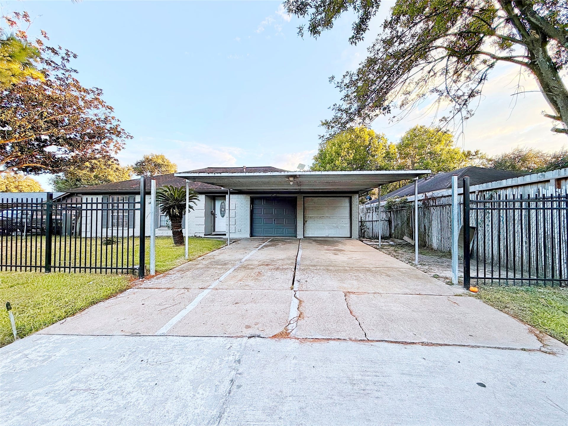 8116 Gulick Lane, Houston, TX 77075 Charming home with a spacious driveway and a secure gated entrance, featuring a two-car carport and lush greenery surrounding the property for added privacy.