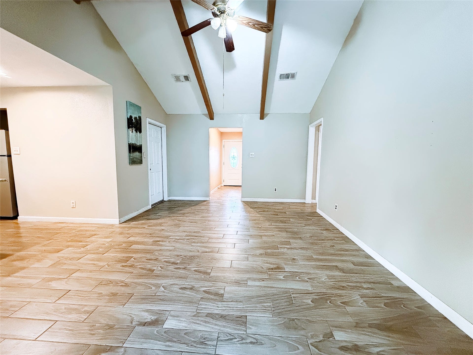 8116 Gulick Lane, Houston, TX 77075 Spacious living area with high vaulted ceilings, exposed wooden beams, and elegant wood-look tile flooring, offering a warm and inviting atmosphere.