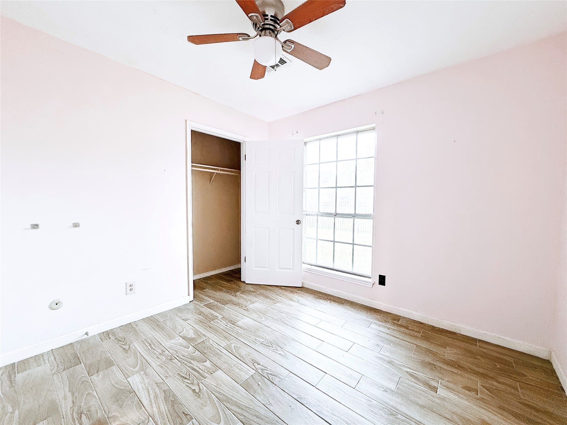 8116 Gulick Lane, Houston, TX 77075 Bright and airy room featuring wood-look tile flooring, a ceiling fan, and a large window for natural light.