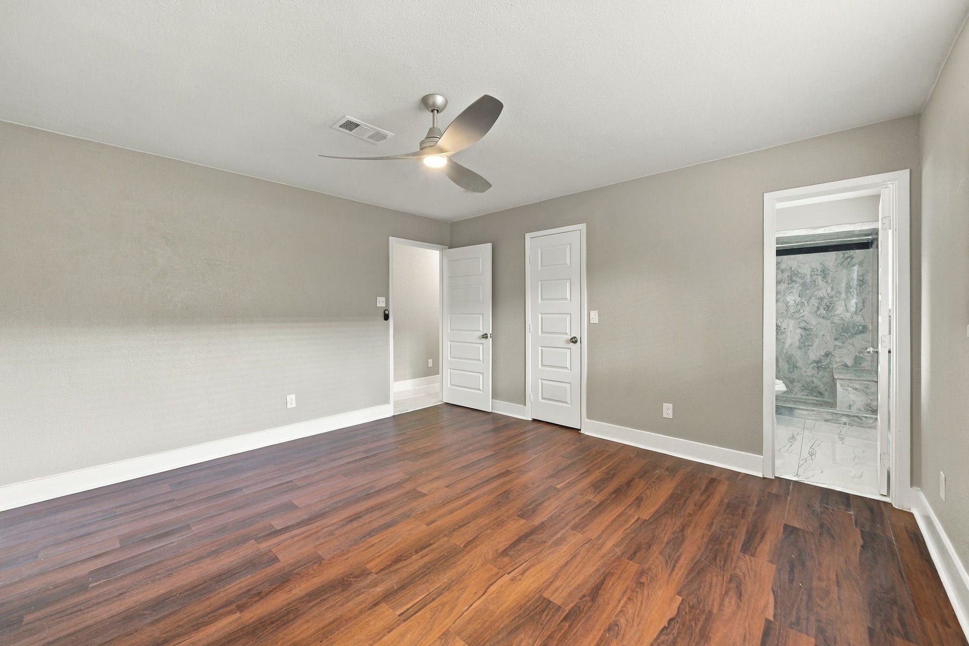 1023 Twinbrooke Drive, Houston, TX 77088 The primary bedroom offers a calm, finished retreat with warm floors and soft neutral styling. Virtually staged.