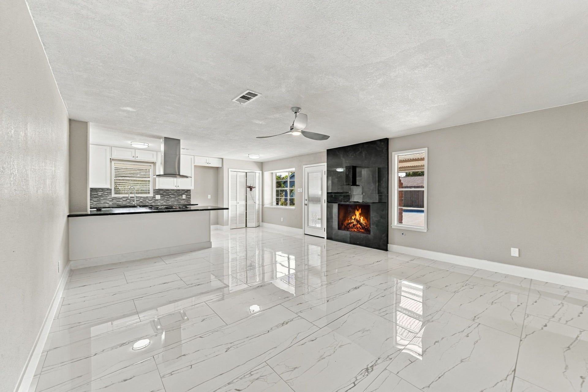 1023 Twinbrooke Drive, Houston, TX 77088 The empty family room shows the fireplace, bright flooring, and easy flow into the kitchen. Virtually staged.