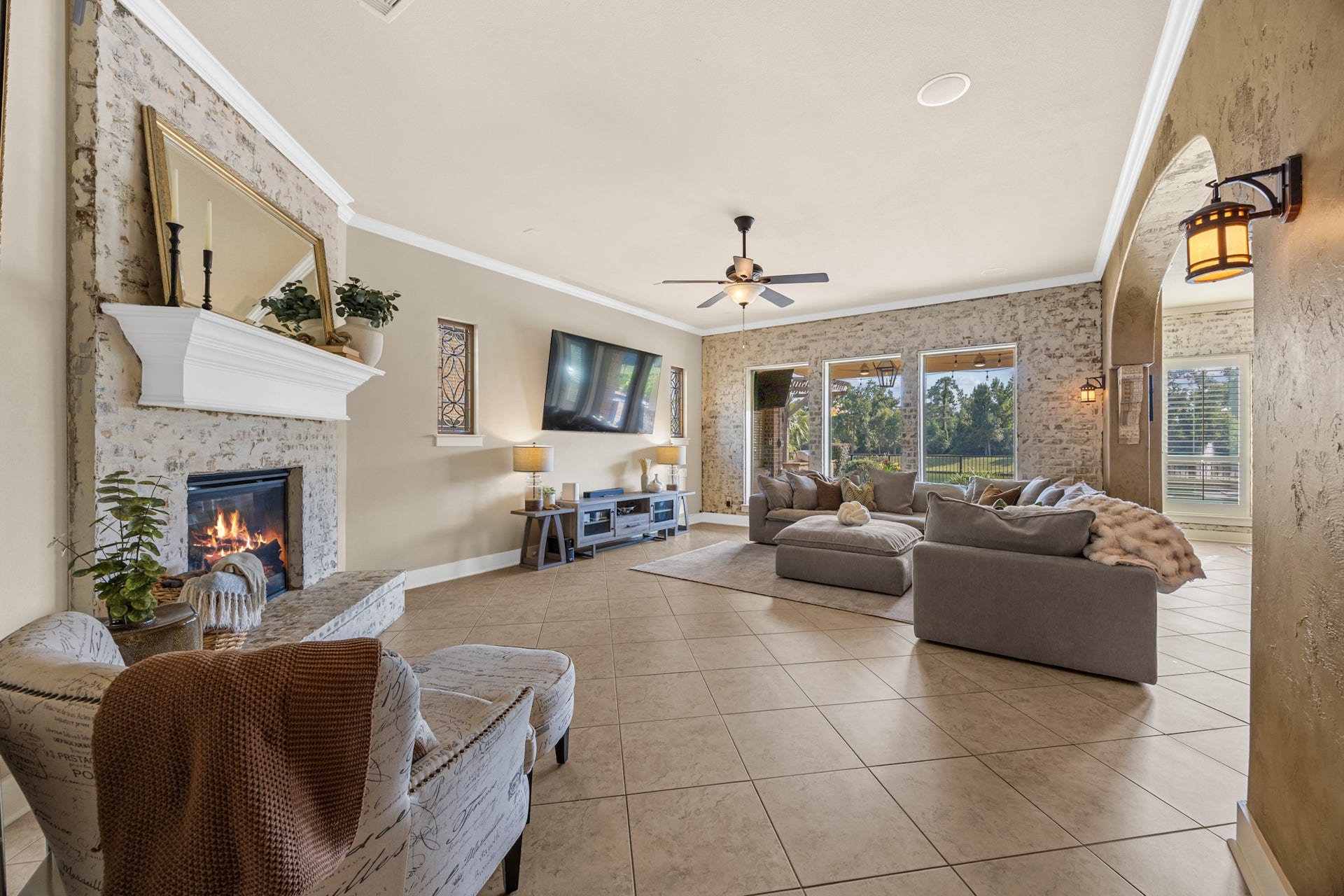 18515 Duke Lake Drive, Spring, TX 77388 Beautifully appointed family room featuring a whitewashed brick fireplace, decorative accent walls, crown molding, and large windows overlooking the backyard.