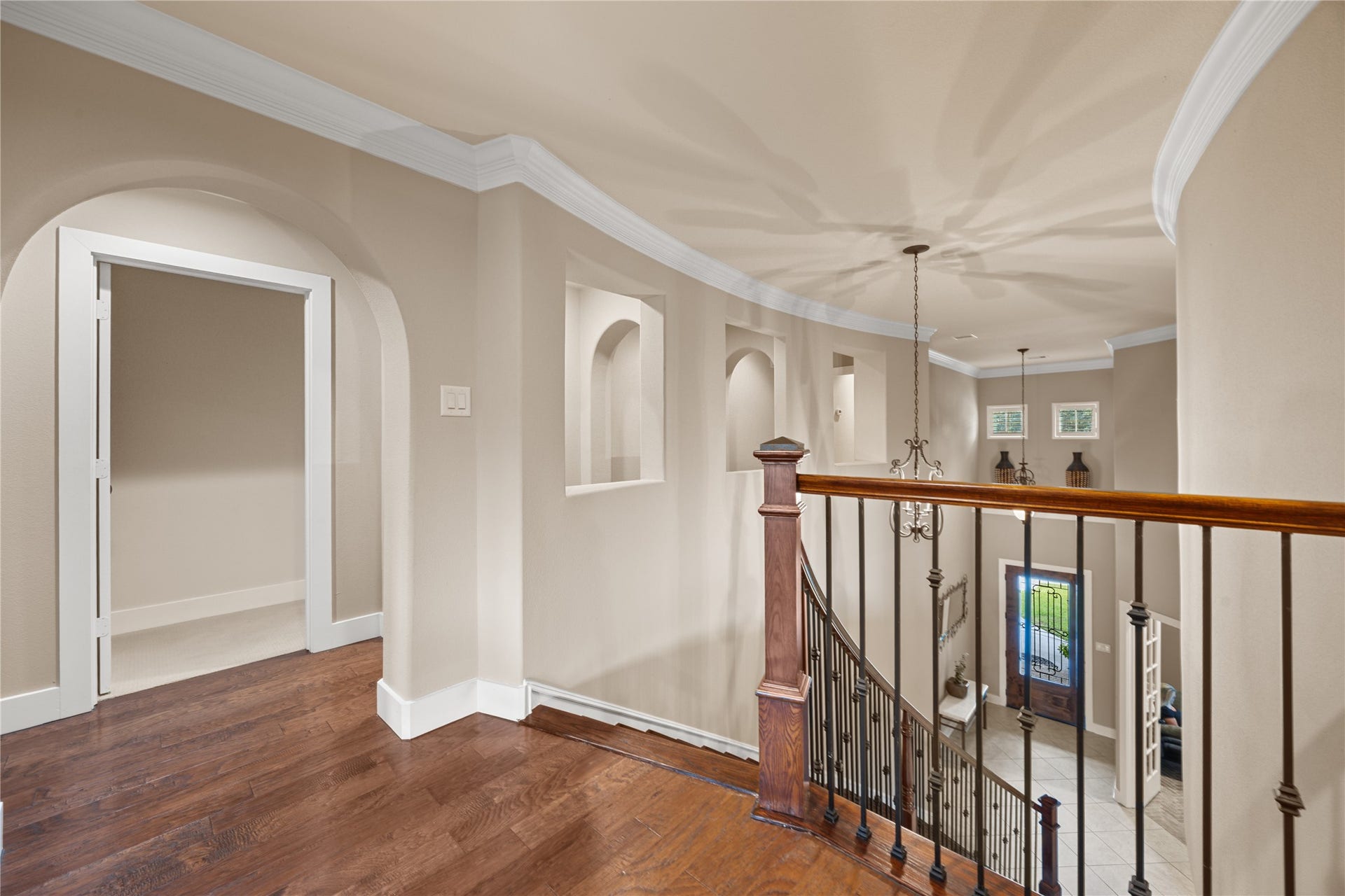 18515 Duke Lake Drive, Spring, TX 77388 Elegant upstairs landing featuring beautiful wood flooring, architectural archways, decorative crown molding, and an open railing overlooking the lower level.