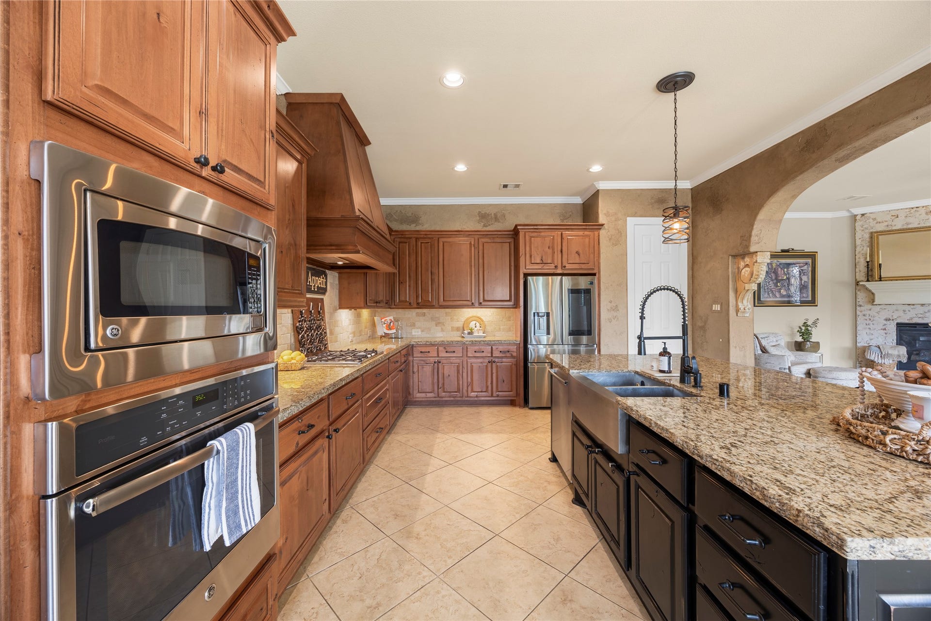 18515 Duke Lake Drive, Spring, TX 77388 Spacious kitchen featuring granite countertops, abundant wood cabinetry, stainless steel appliances, a double-basin farmhouse sink, and an oversized island.