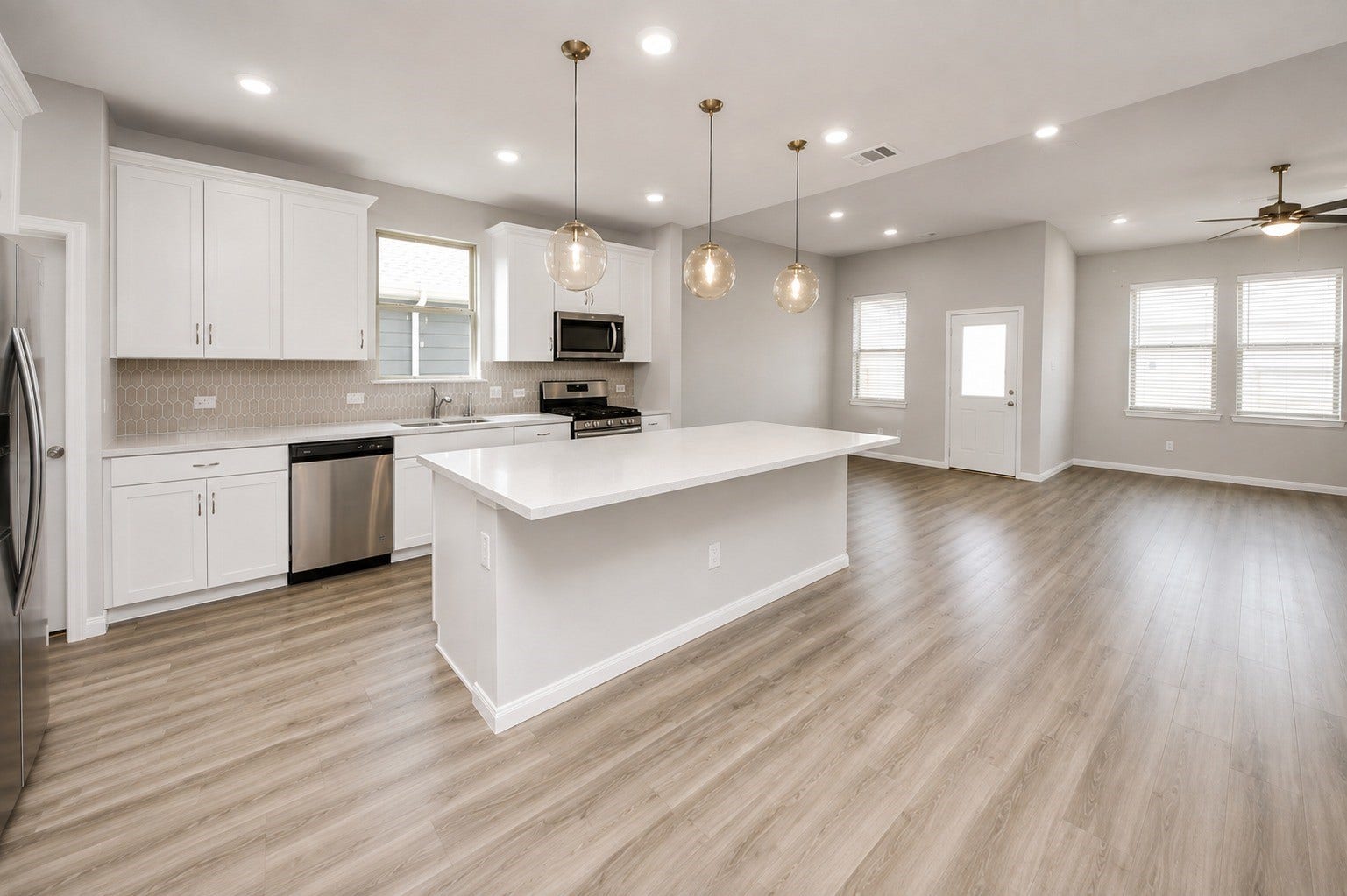 1311 Bonnerjee Drive, Crosby, TX 77532 Spacious open concept kitchen featuring a large center island, quartz countertops, white cabinetry, stainless steel appliances, and abundant natural light.