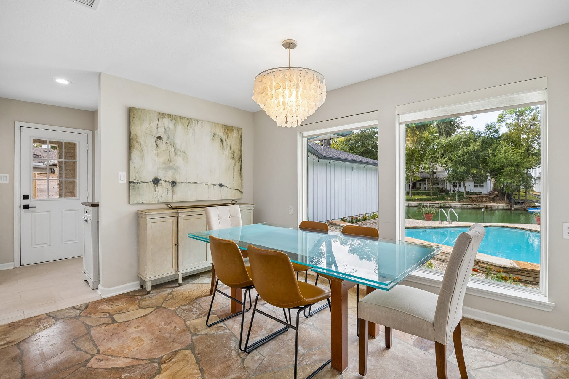 12314 Honeywood Trail, Houston, TX 77077 Light-filled eating area featuring original stone flooring, expansive windows overlooking the pool and lake, and a convenient side door providing direct access to he driveway.