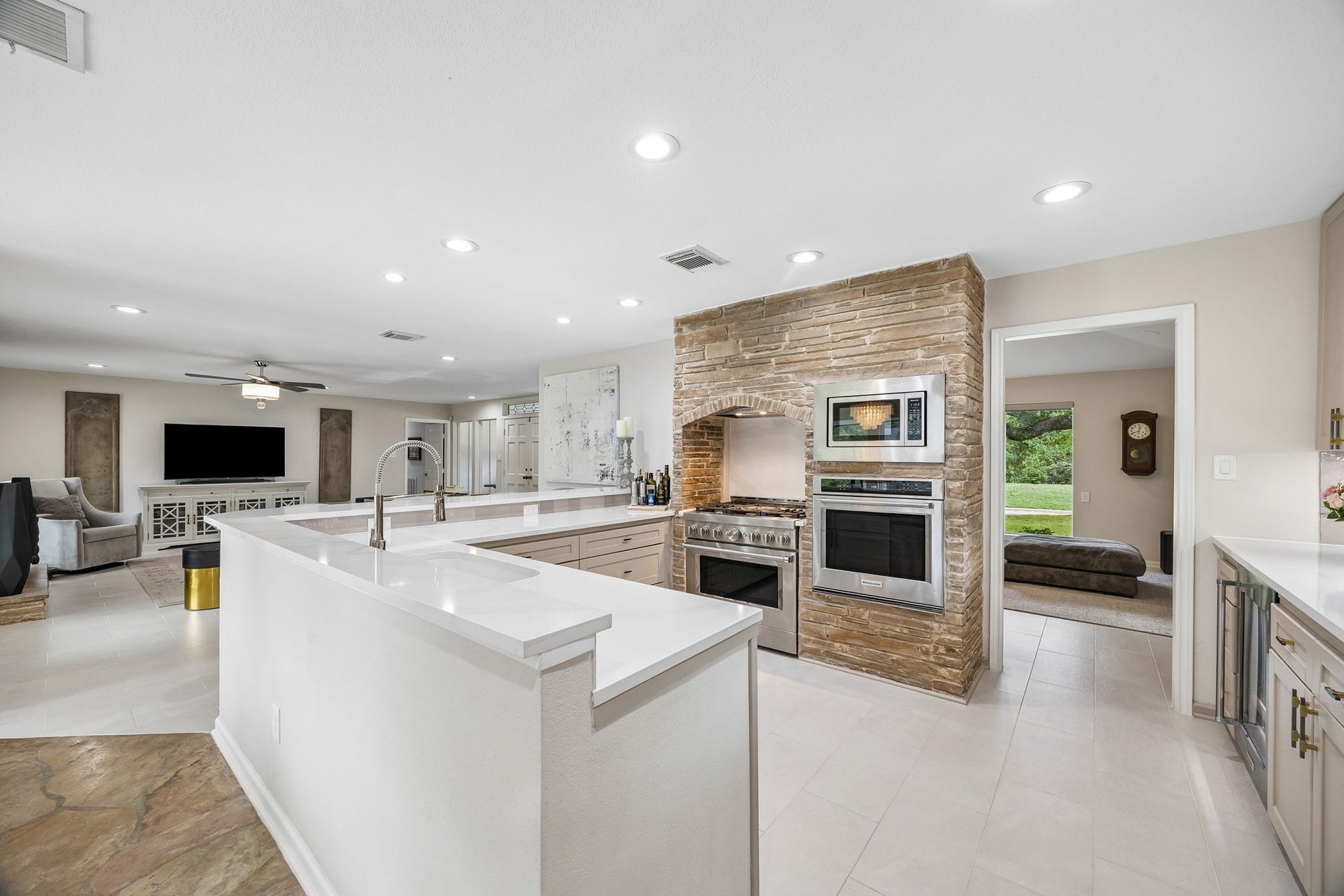 12314 Honeywood Trail, Houston, TX 77077 Beautifully appointed kitchen featuring a striking stone-accented wall, a KitchenAid stainless steel appliance suite, with a wall oven, microwave, range with 6-burner gas cooktop, dishwasher, and beverage chiller. A perfect blend of modern elegance and timeless warmth.