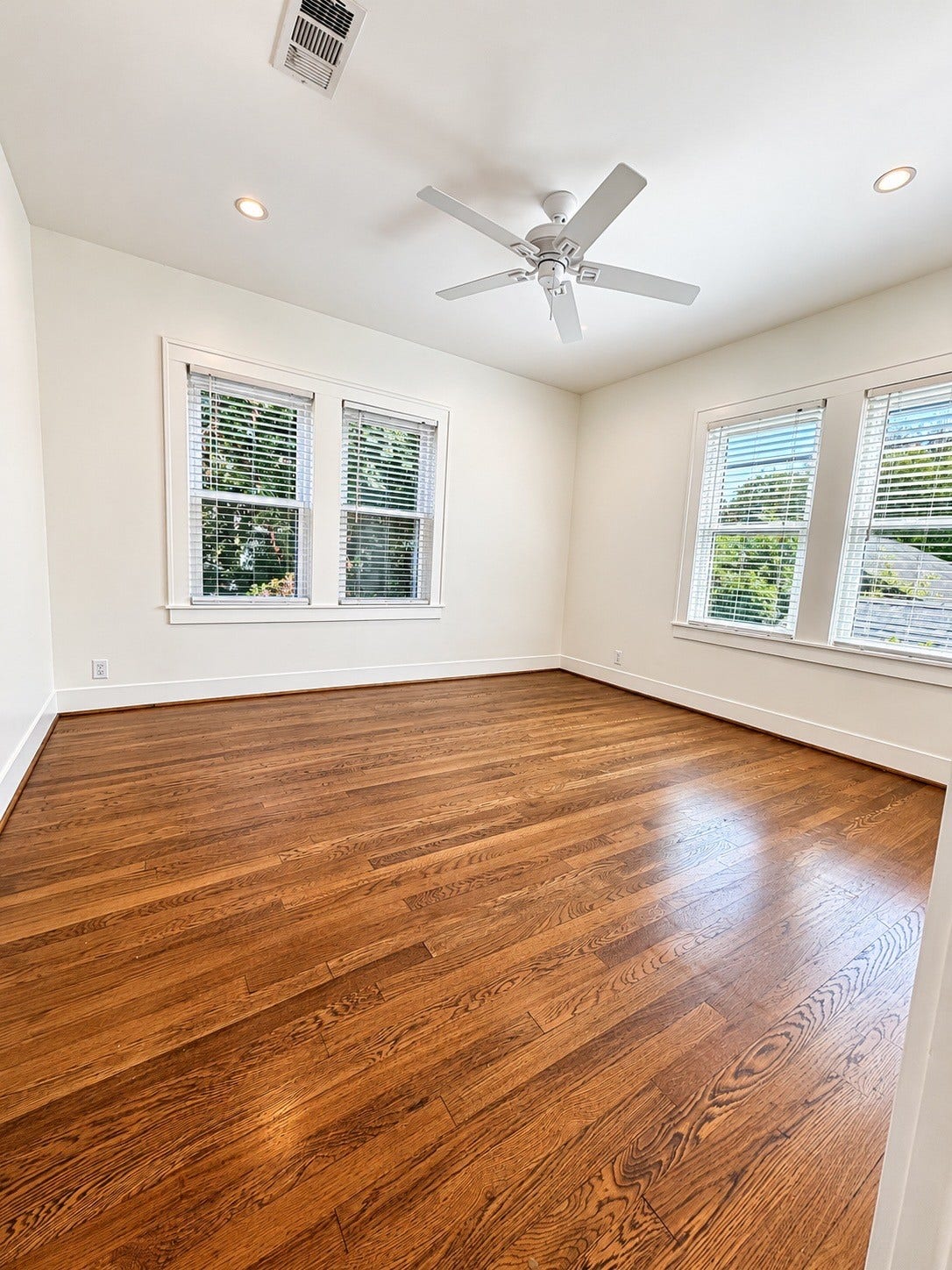 914.5 W Melwood Street, Houston, TX 77009 Generously sized bedroom with hardwood floors, ceiling fan, and natural light from windows on two walls.