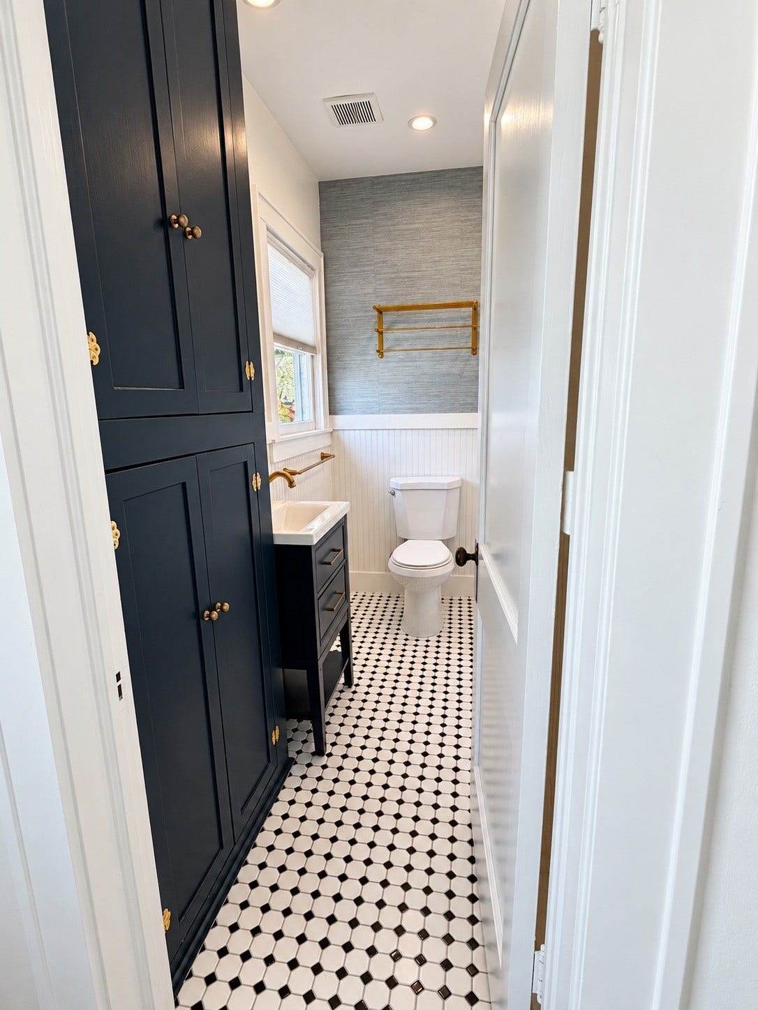 914.5 W Melwood Street, Houston, TX 77009 Updated bathroom featuring patterned tile, rich navy cabinetry, brass fixtures, and stylish finishes.
