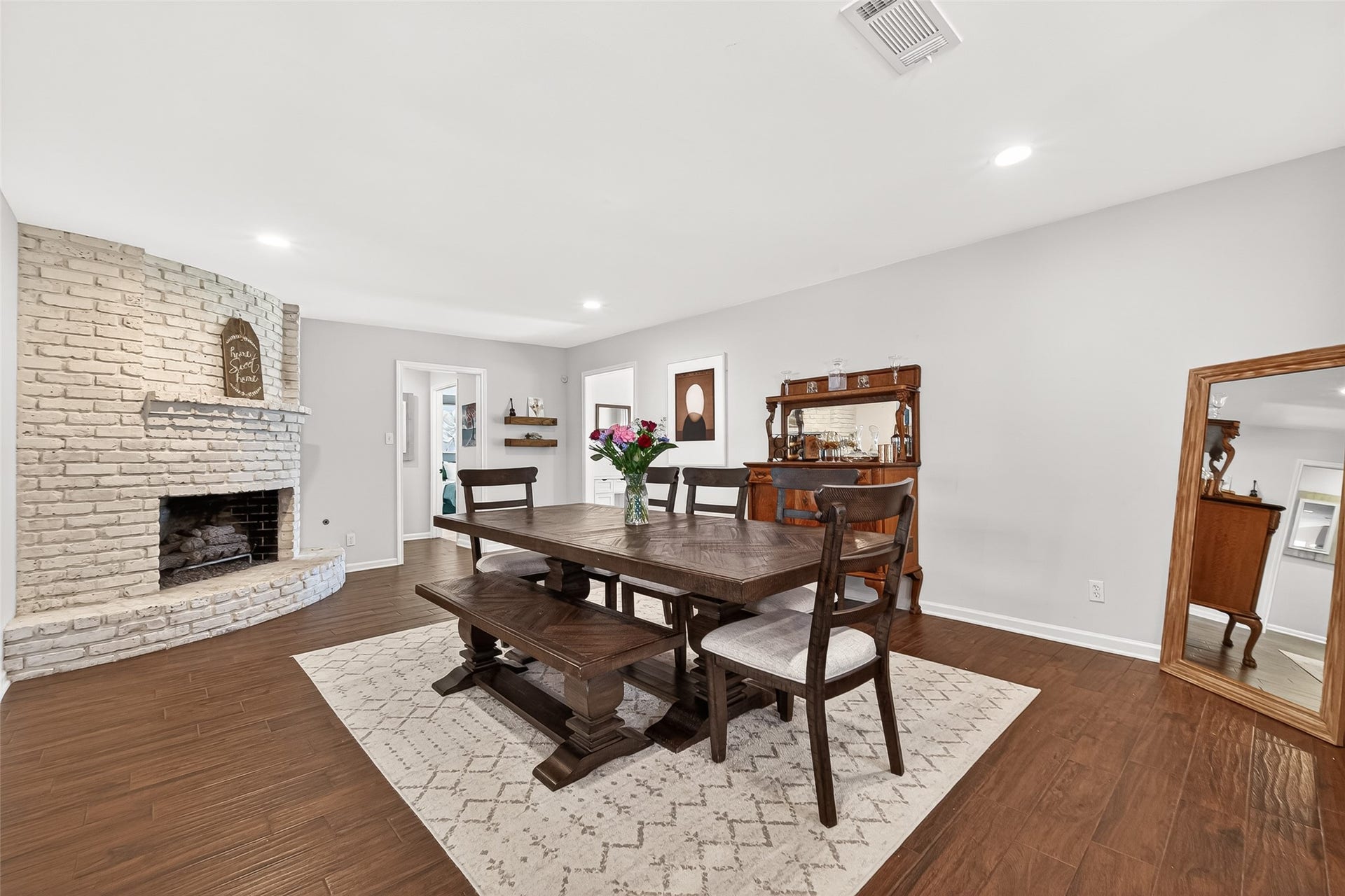 2610 Teague Road, Houston, TX 77080 This inviting dining room features a cozy white brick fireplace, and beautiful wood-like tile floors. It offers a warm and welcoming atmosphere, perfect for family gatherings.