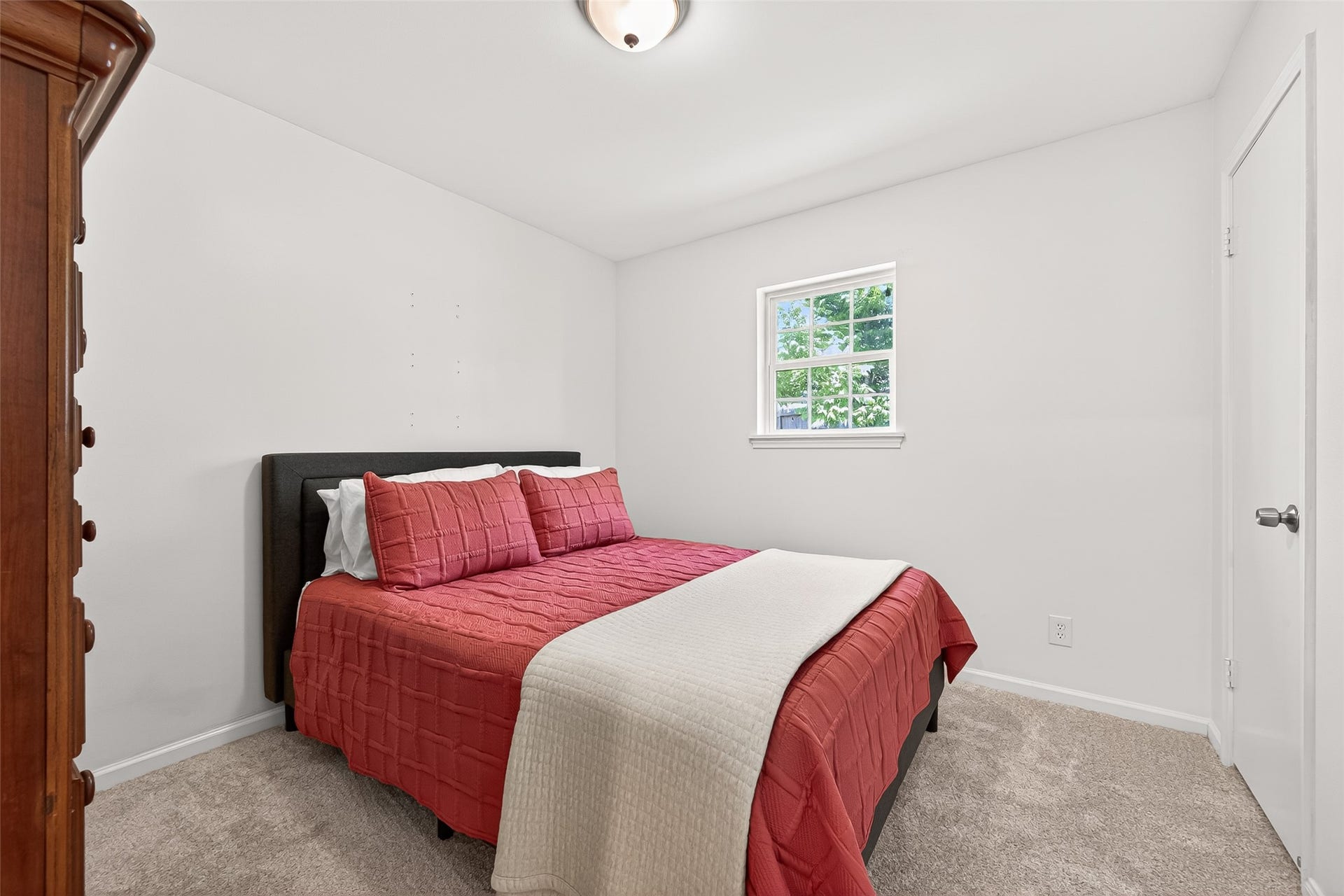 2610 Teague Road, Houston, TX 77080 Secondary bedroom with a soft, neutral color palette. A window allows natural light to brighten the space, complemented by carpeted flooring and simple decor.