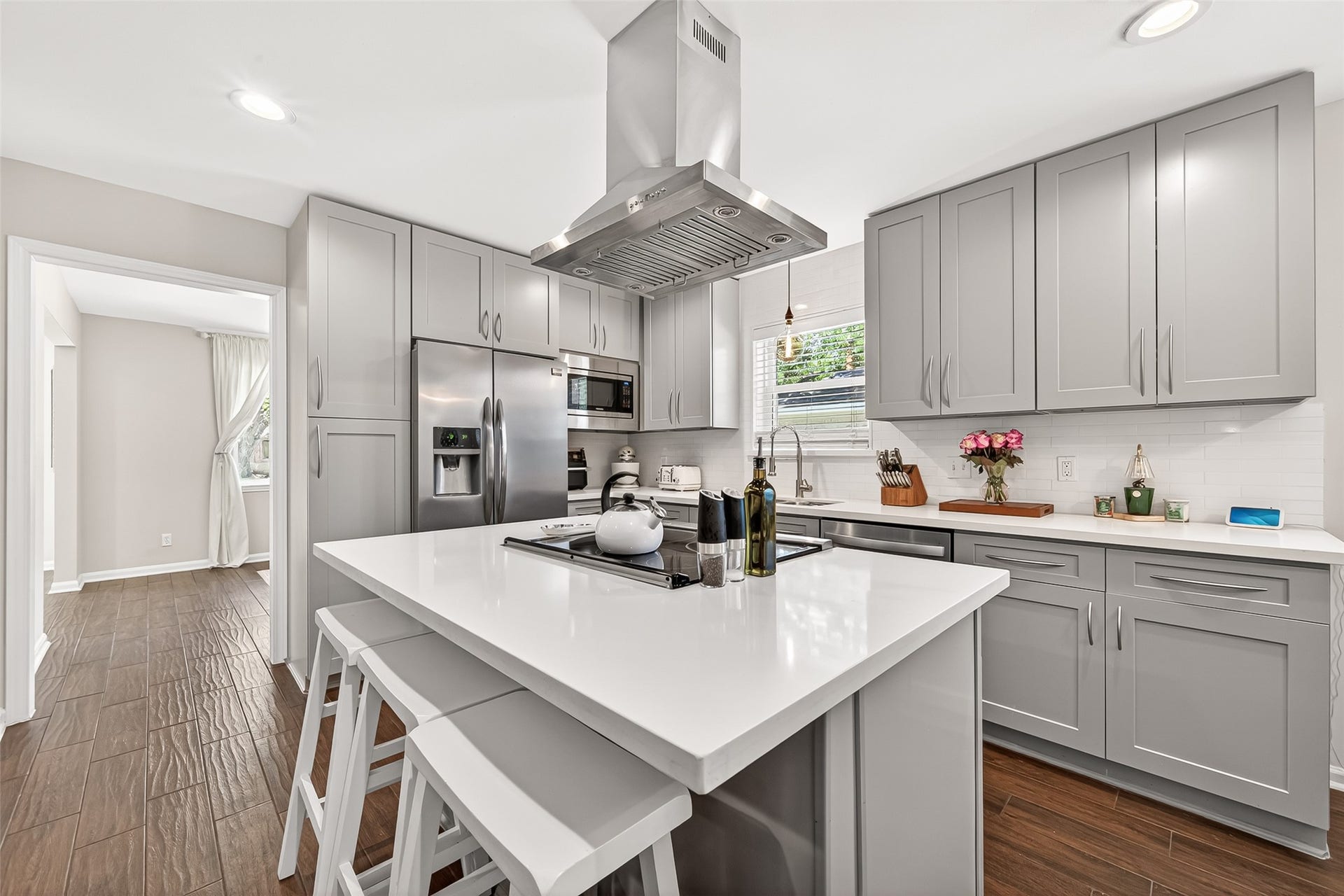 2610 Teague Road, Houston, TX 77080 This modern kitchen features sleek gray cabinetry, stainless steel appliances, and a central island with bar seating.