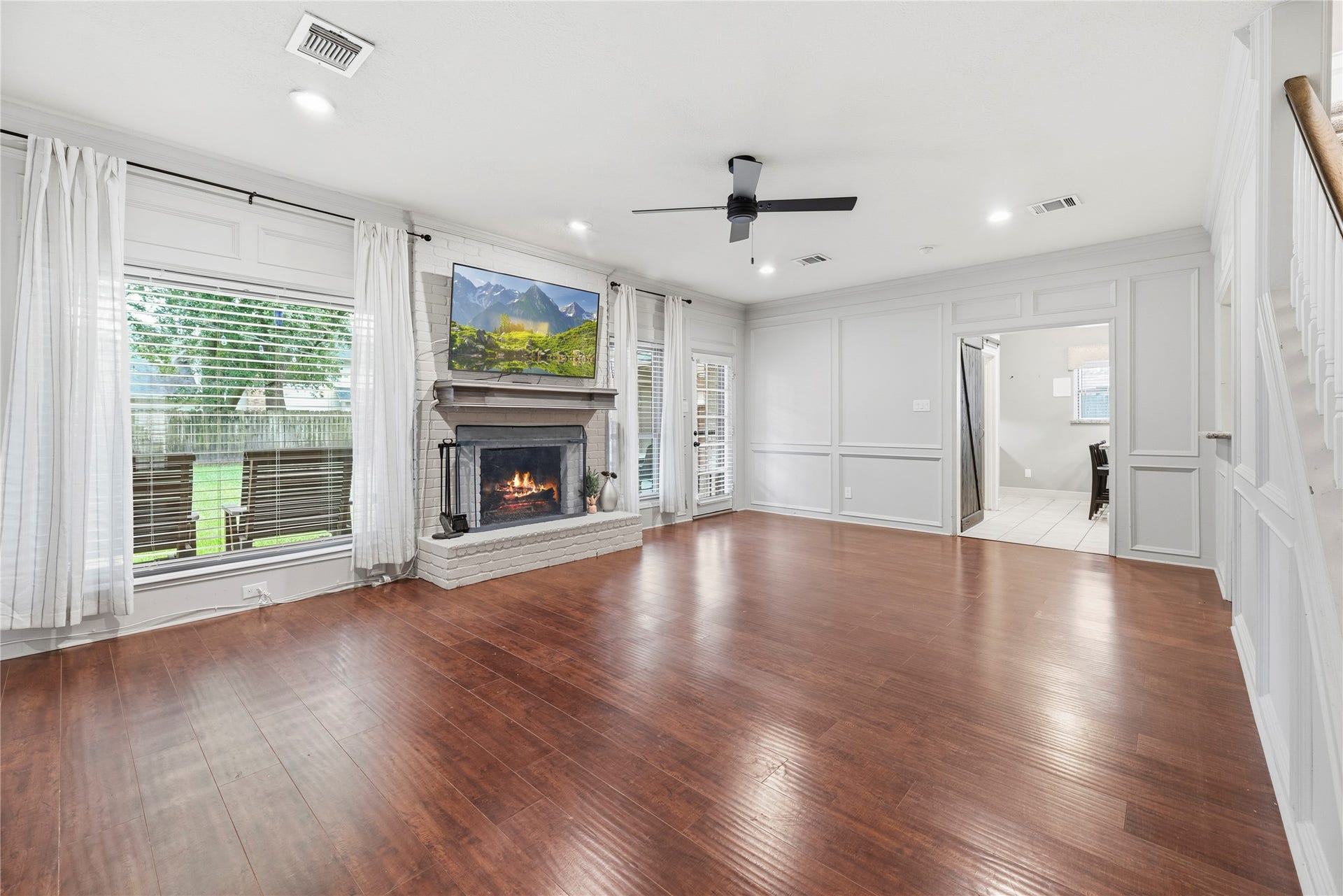 The family room boasts wood flooring, crown molding, ceiling fan, wet bar and a cozy fireplace with brick surround.
