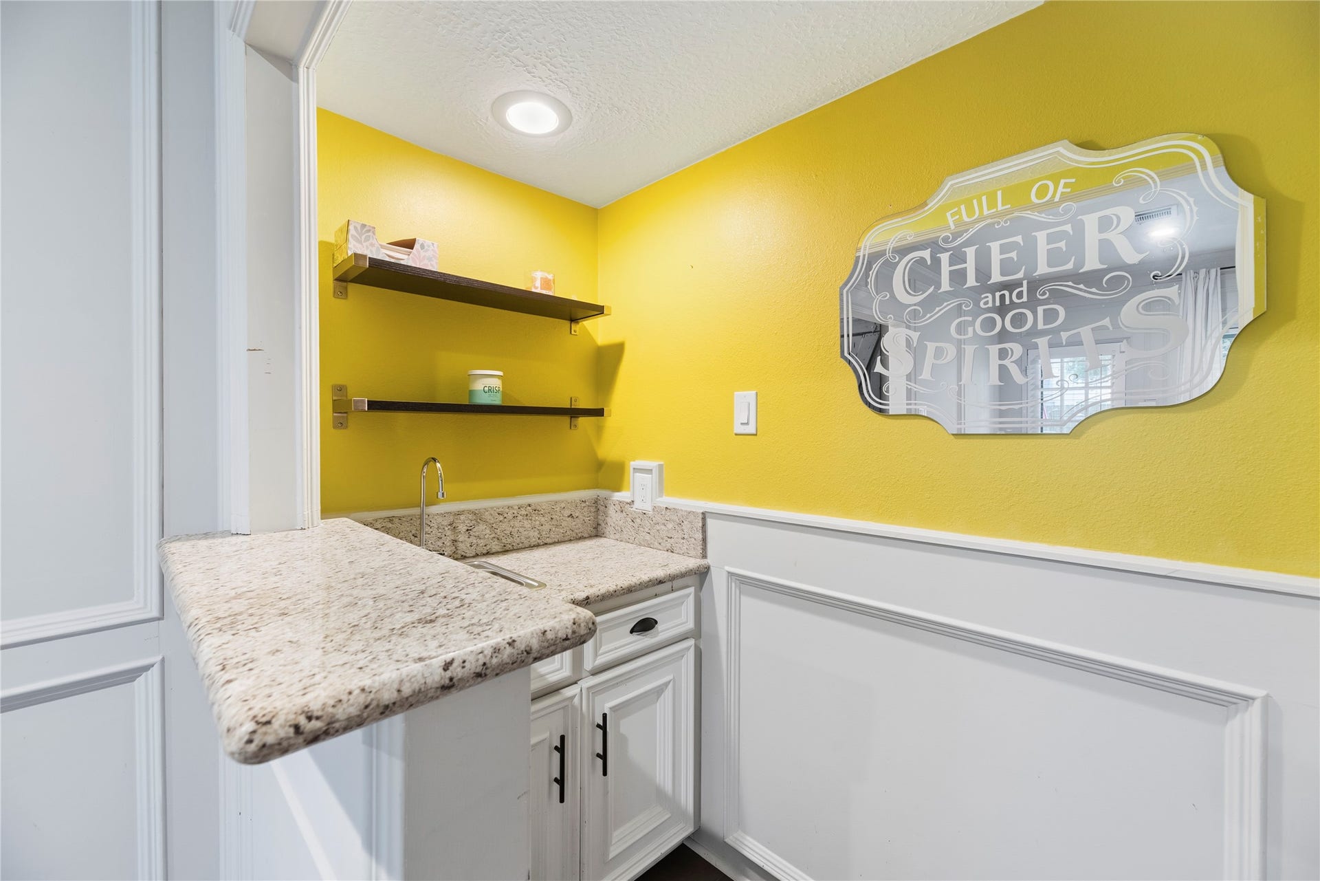 Wet bar area with granite counters and additional storage.