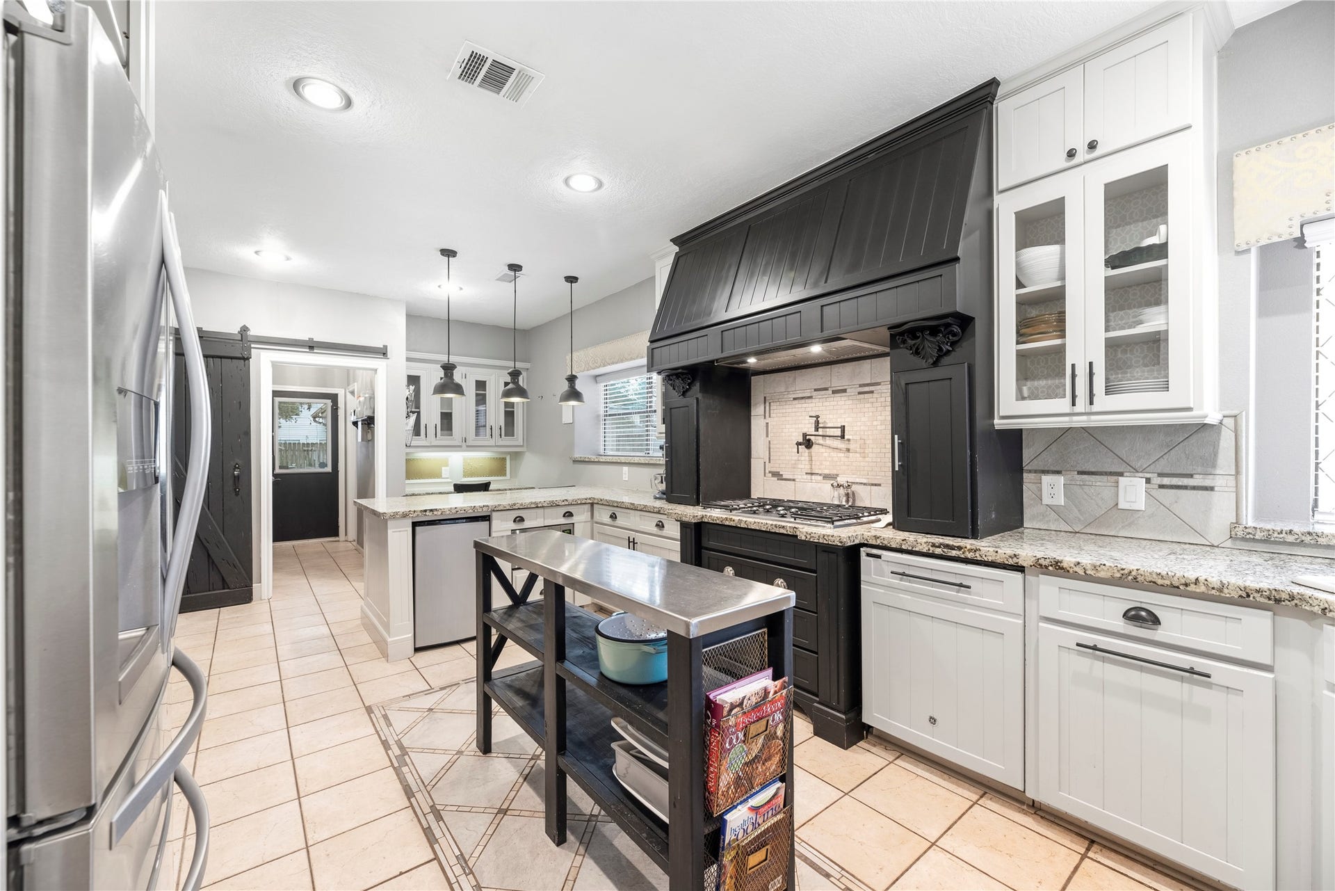 Gourmet kitchen features gorgeous granite countertops, white cabinetry, stainless steel appliances, double ovens, gas cooktop and a convenient pot filler.
