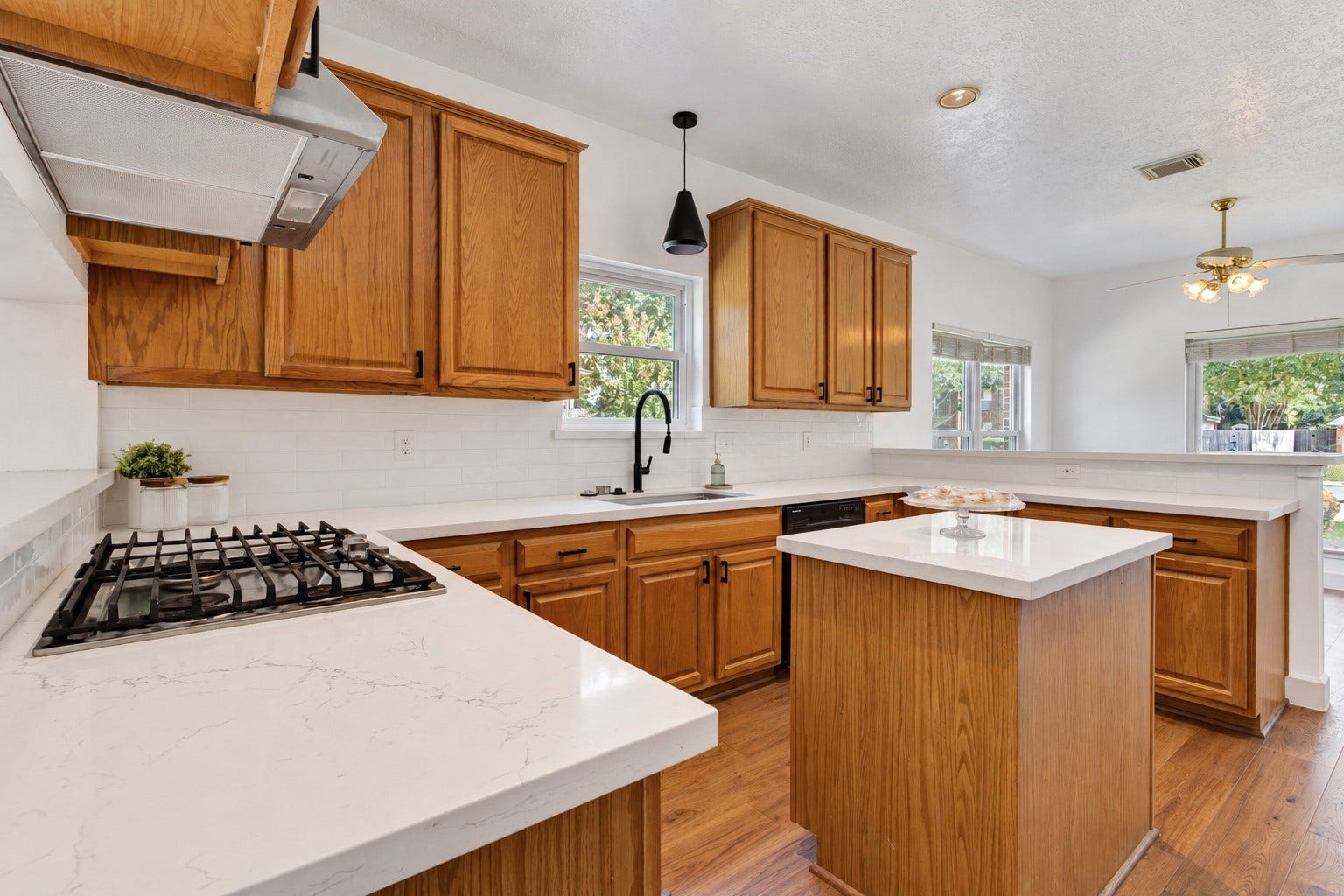 304 Melodywood Drive, Friendswood, TX 77546 This inviting kitchen pairs warm wood cabinetry with quartz countertops, a crisp white subway tile backsplash, and contrasting black hardware. A gas cooktop, center island, and generous counter space make meal preparation easy, while abundant cabinetry provides ample storage. Natural light and an open connection to the breakfast area create a welcoming space for everyday dining and gathering.