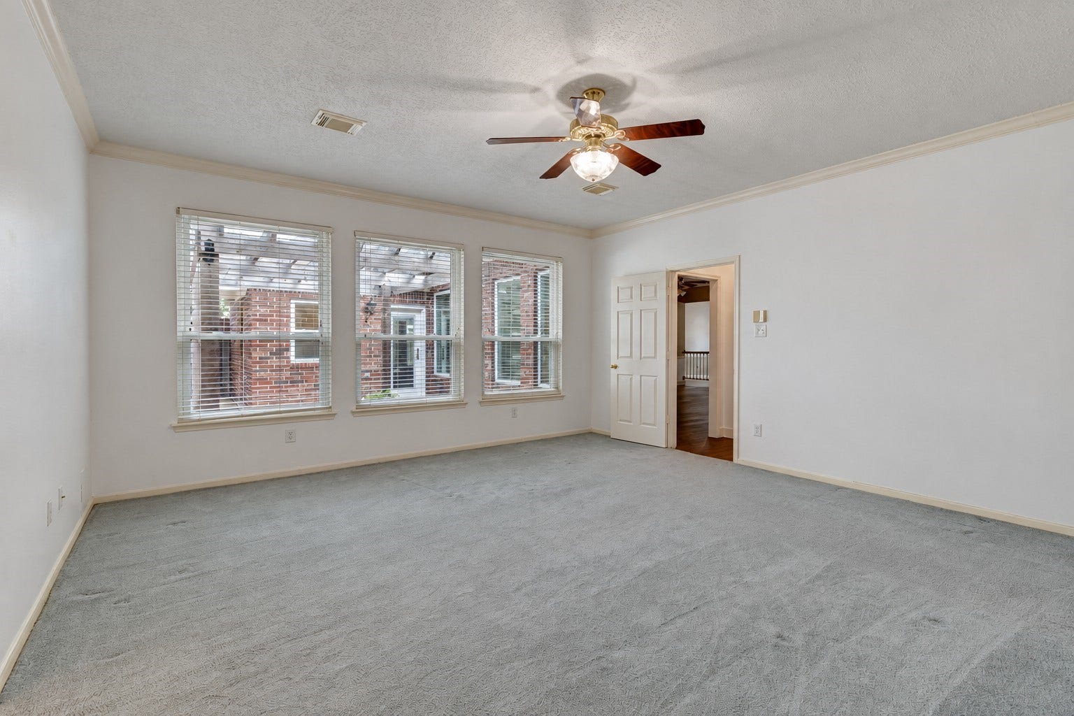 304 Melodywood Drive, Friendswood, TX 77546 The spacious primary bedroom offers plenty of room for a king-size bed and additional furnishings. Three large windows bring in natural light, while soft carpeting, neutral walls, crown molding, and a ceiling fan create a comfortable retreat.