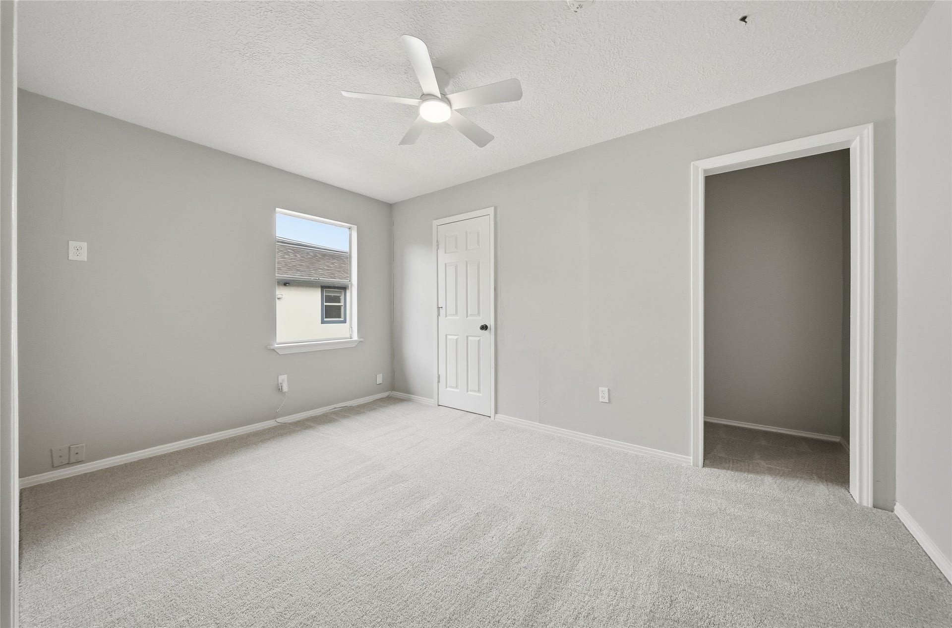 Bright and airy bedroom featuring fresh neutral paint, plush carpeting, a modern ceiling fan, and great closet space.