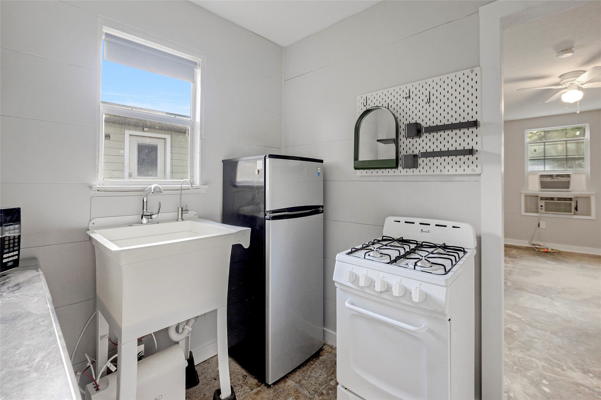 Cozy utility area with a compact fridge, gas stove, and deep wash sink, ideal for efficient living.