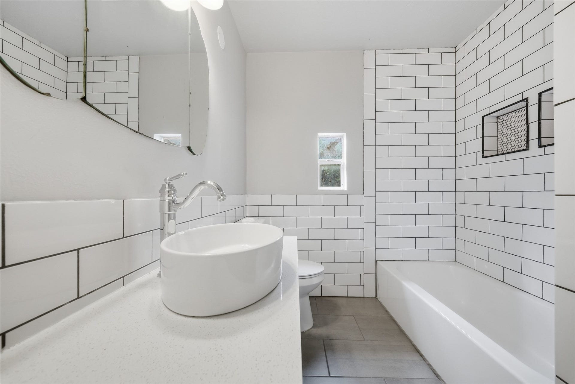 Modern bathroom featuring sleek white subway tiles, a stylish vessel sink, and a spacious bathtub, creating a clean and contemporary look.