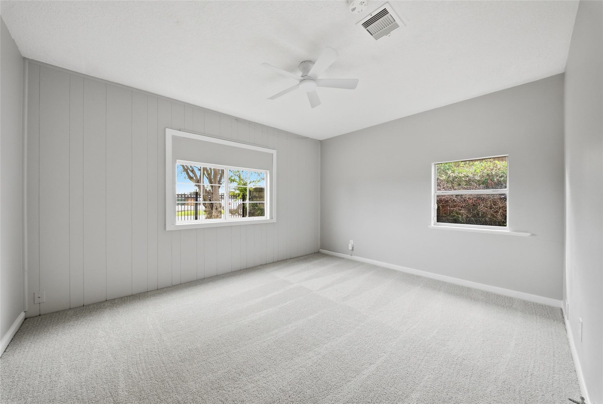 Bright and spacious bedroom featuring neutral tones, plush carpeting, and large windows that invite plenty of natural light.