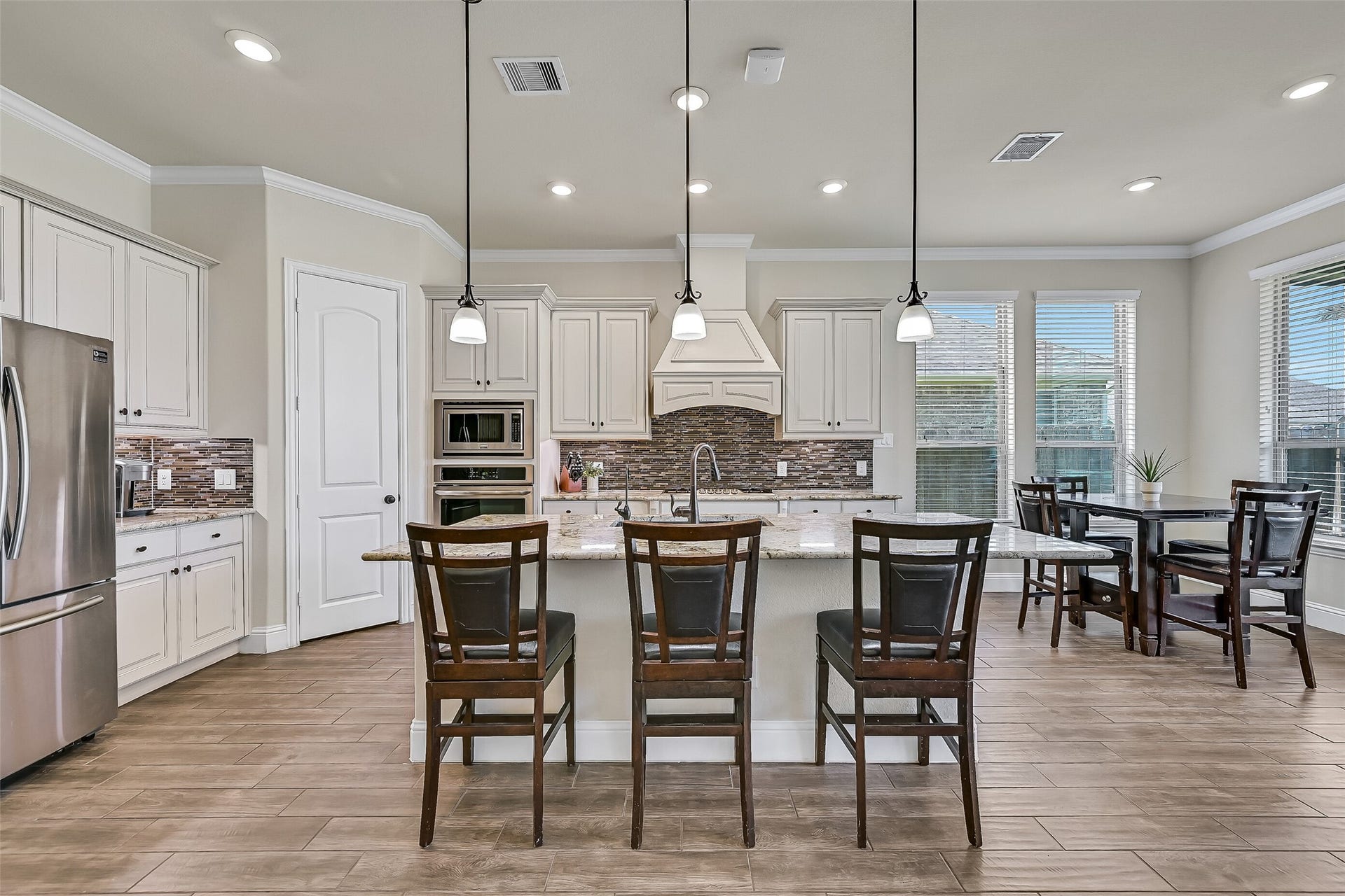 1645 Longwood Glen Lane, Friendswood, TX 77546 Designed for gathering, this spacious island kitchen offers seating for four, granite countertops, a five-burner gas cooktop, built-in oven and microwave, under-cabinet lighting, abundant cabinetry, and a walk-in corner pantry. The breakfast area overlooks the backyard, making everyday meals feel bright and inviting.
