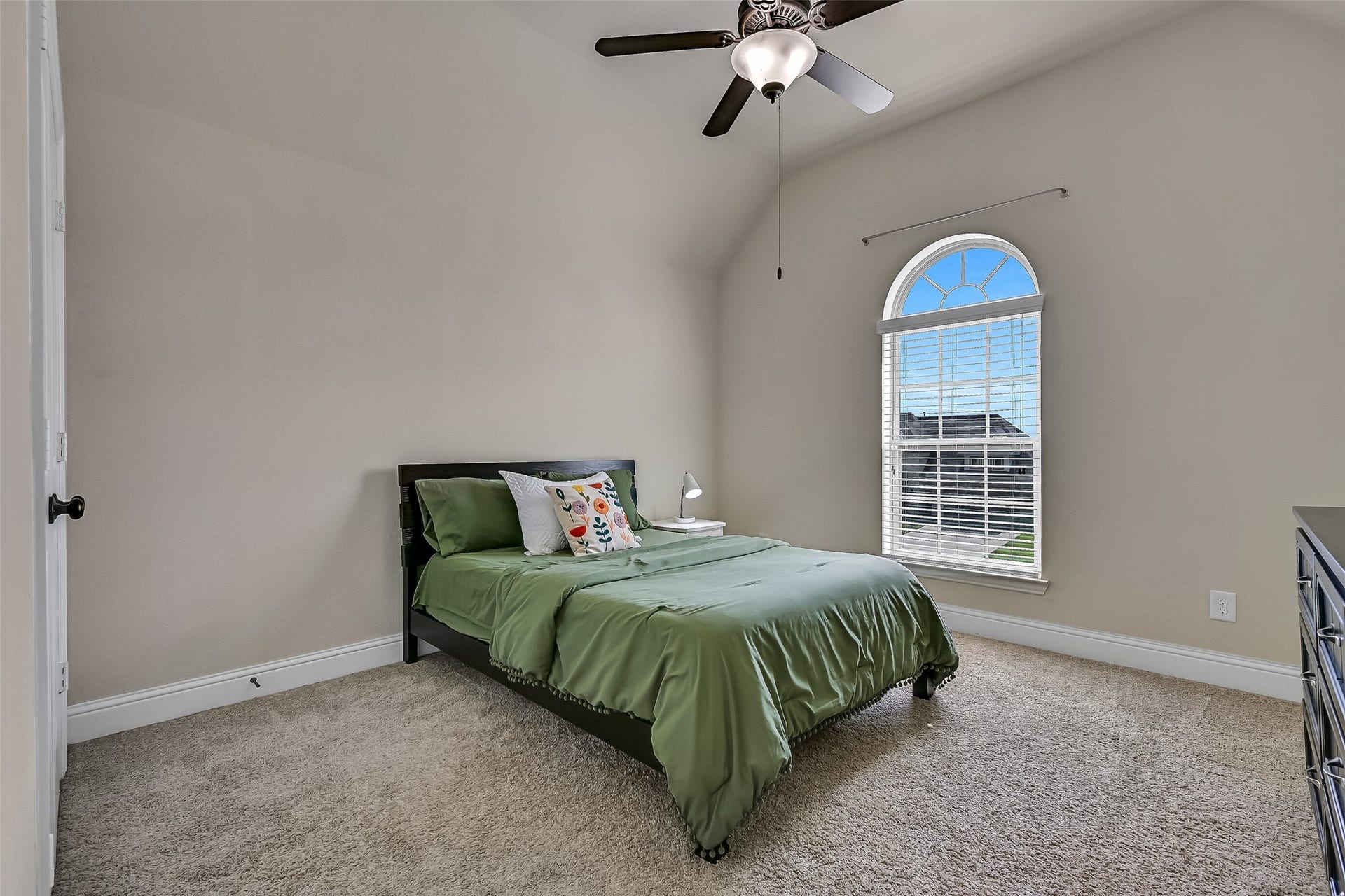 1645 Longwood Glen Lane, Friendswood, TX 77546 Just off the game room, this spacious secondary bedroom offers vaulted ceilings, plush carpeting, a lighted ceiling fan, and a charming arched window that fills the room with natural light. With its own nearby full bath, it provides comfort and privacy for family members or overnight guests.