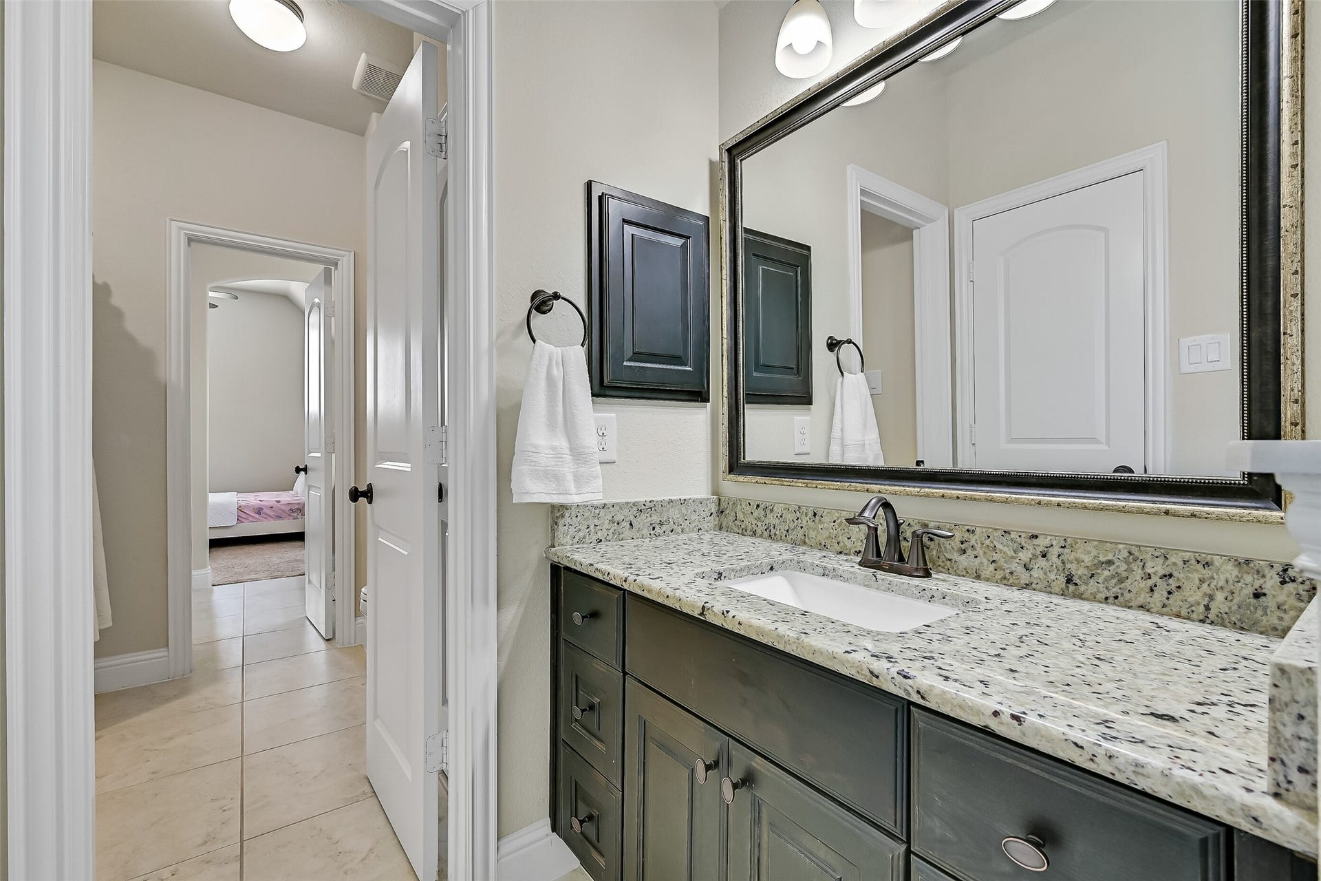 1645 Longwood Glen Lane, Friendswood, TX 77546 Designed for both convenience and privacy, the Jack-and-Jill bath features a granite vanity with an undermount sink, stained wood cabinetry, oil-rubbed bronze fixtures, and direct access from each adjoining bedroom. The thoughtful layout makes sharing easy while giving everyone their own space.