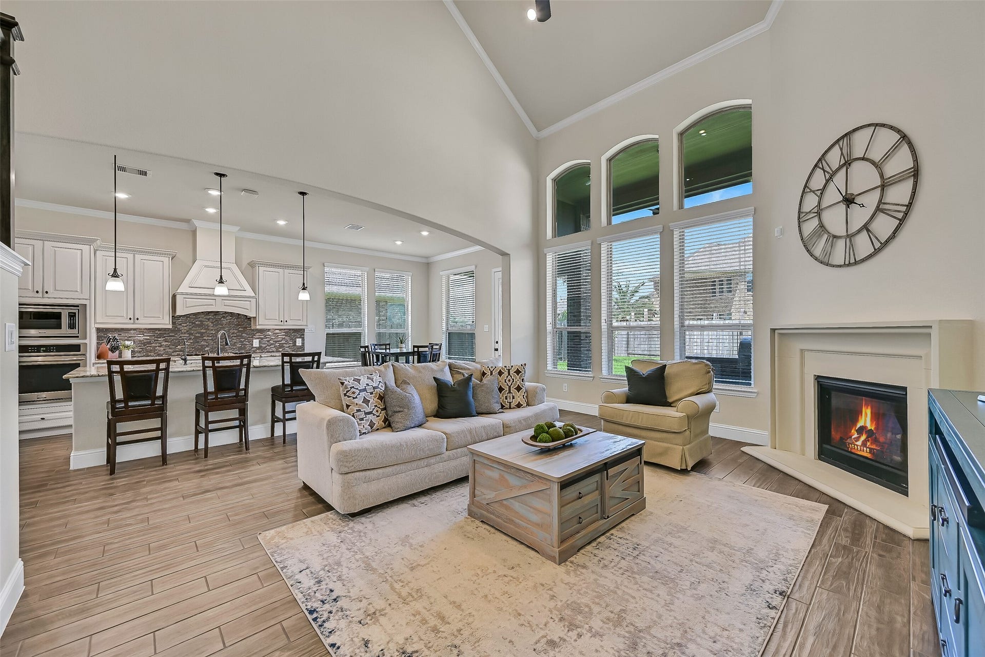 1645 Longwood Glen Lane, Friendswood, TX 77546 The heart of the home welcomes you with soaring 20-foot ceilings, a dramatic wall of windows that fills the space with natural light, and a cast stone gas log fireplace that creates a warm focal point. Wood-look tile flooring and an open layout seamlessly connect the family room to the kitchen and breakfast area.
