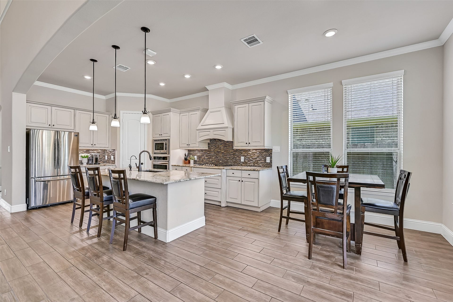 1645 Longwood Glen Lane, Friendswood, TX 77546 The spacious island kitchen is thoughtfully designed with seating for four, granite countertops, abundant cabinetry, and a seamless connection to the breakfast area. Pendant lighting, under-cabinet lighting, and windows overlooking the backyard create a bright, welcoming space for everyday living.