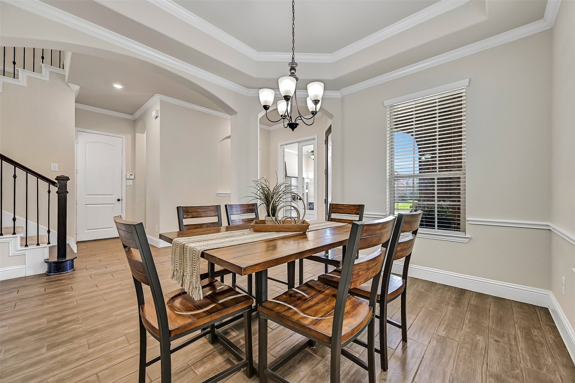 1645 Longwood Glen Lane, Friendswood, TX 77546 Whether hosting holiday dinners or intimate gatherings, the formal dining room provides an elegant setting with a tray ceiling, crown molding, wood-look tile flooring, abundant natural light from front and side-facing windows, and a timeless iron chandelier.
