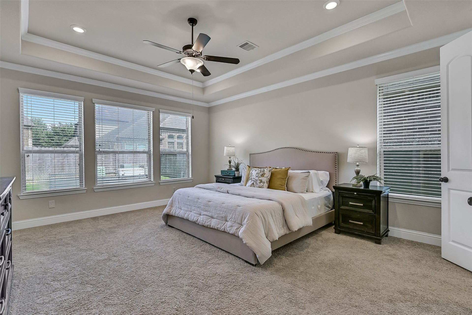 1645 Longwood Glen Lane, Friendswood, TX 77546 Privately tucked away on the first floor, the spacious primary suite features an elegant tray ceiling with crown molding, plush carpeting, and a wall of rear-facing windows that bring in soft natural light. The generous layout easily accommodates large furnishings while creating a peaceful retreat at the end of the day.