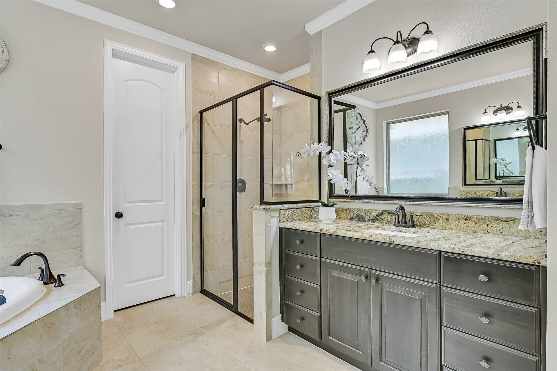 1645 Longwood Glen Lane, Friendswood, TX 77546 Start and end each day in a bathroom designed for comfort, featuring expansive granite countertops, abundant storage, elegant oil-rubbed bronze fixtures, and a spacious walk-in shower finished with timeless tile, a sleek glass enclosure, & a water softening system on the home.