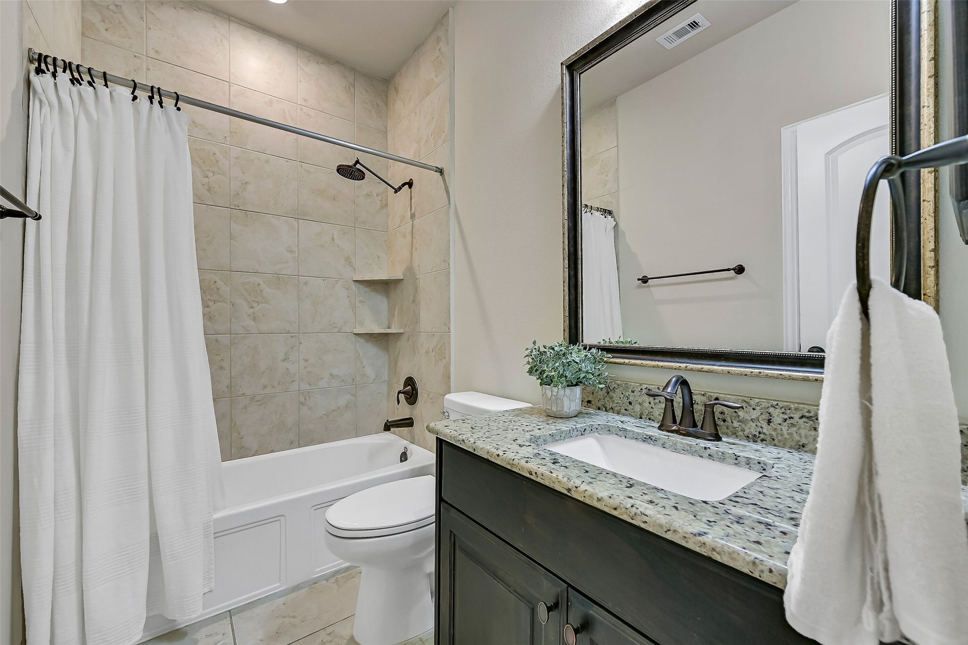 1645 Longwood Glen Lane, Friendswood, TX 77546 Conveniently located adjacent to the game room and nearby bedroom, this full bath features a granite vanity with a rectangular undermount sink, framed mirror, stained wood cabinetry, and a tub/shower with a tile surroundperfect for everyday use or accommodating overnight guests.