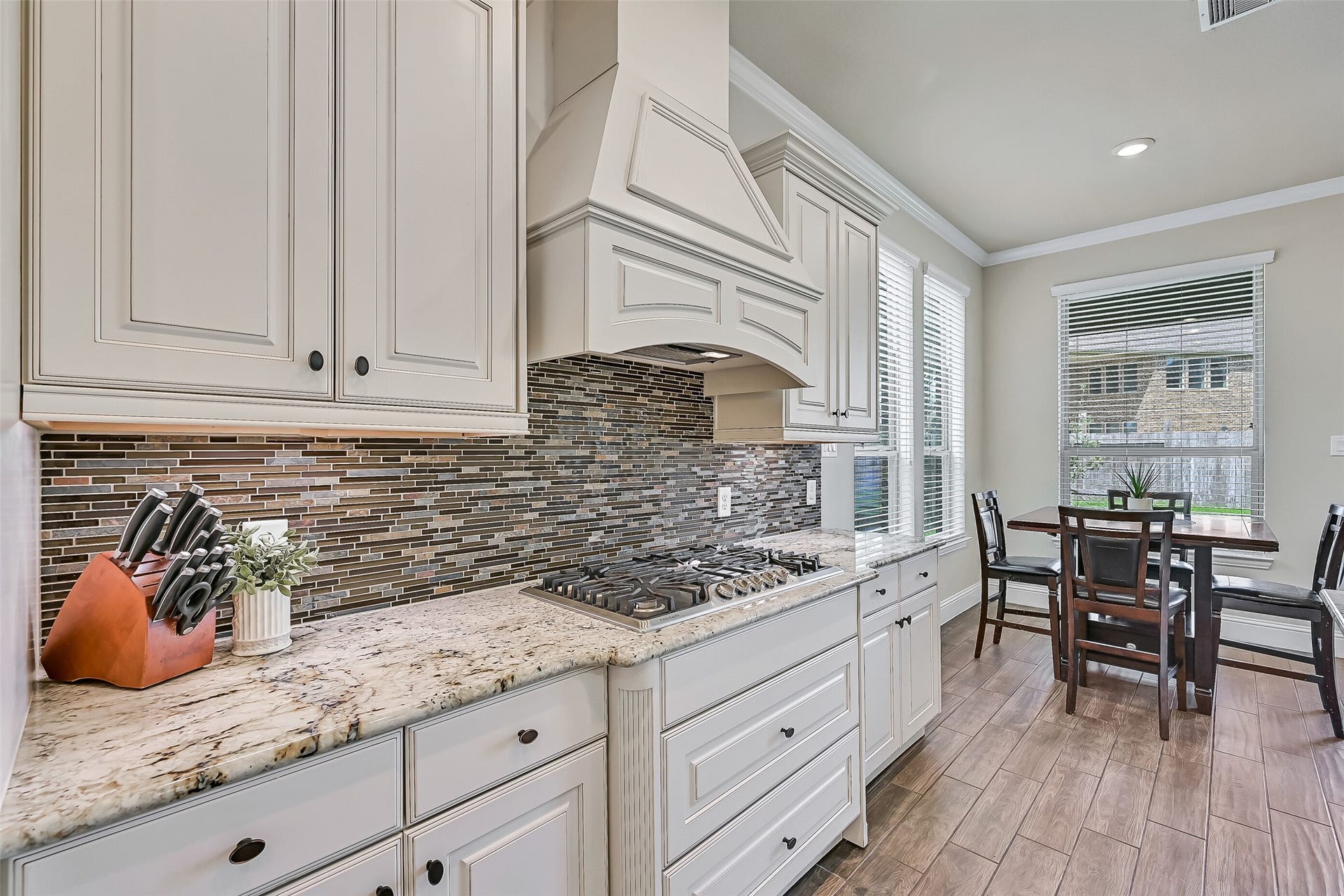 1645 Longwood Glen Lane, Friendswood, TX 77546 A beautiful glass and stone mosaic backsplash complements the custom vent hood, while extensive cabinetry, generous prep space, and an open layout make this kitchen equally suited for weeknight dinners and holiday gatherings.