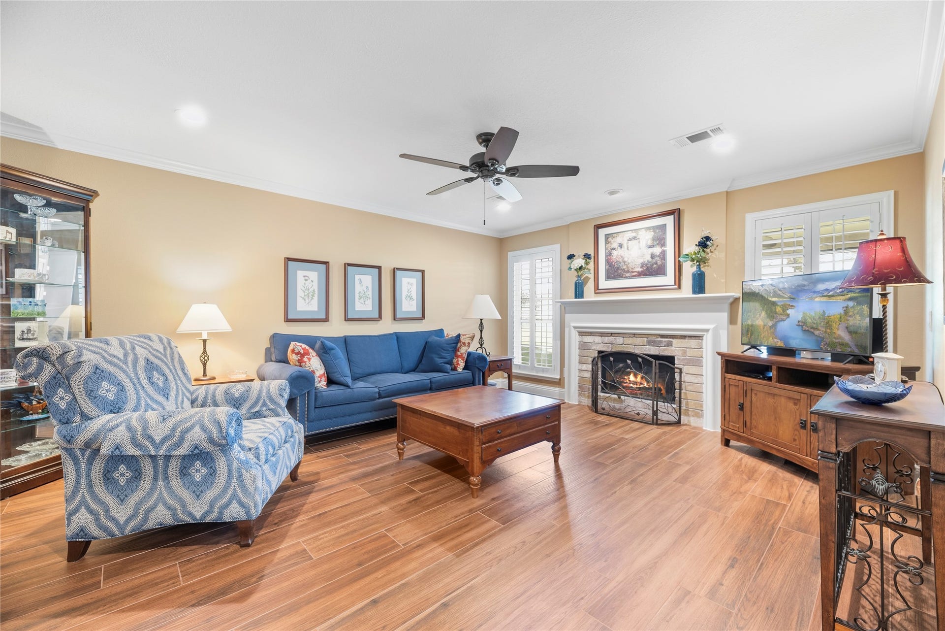 17906 Lone River Court, Houston, TX 77095 Spacious family room offers crown molding, ceiling fan, window shutters, wood-look tile flooring and a cozy fireplace with brick surround.