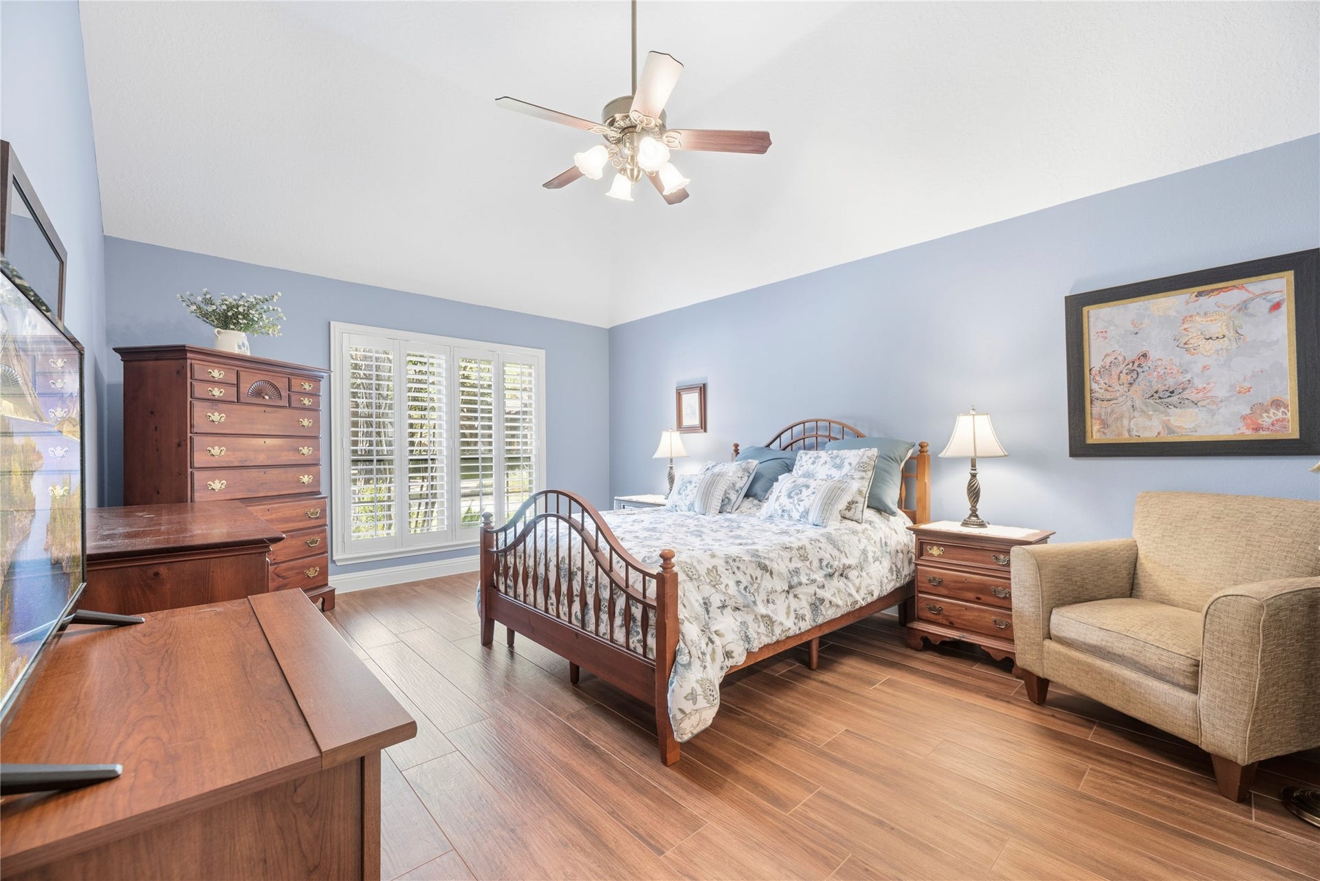 17906 Lone River Court, Houston, TX 77095 Inviting primary suite featuring a high ceiling, rich wood-look tile flooring, window shutters and plenty of natural light, with ample room for a comfortable sitting area.