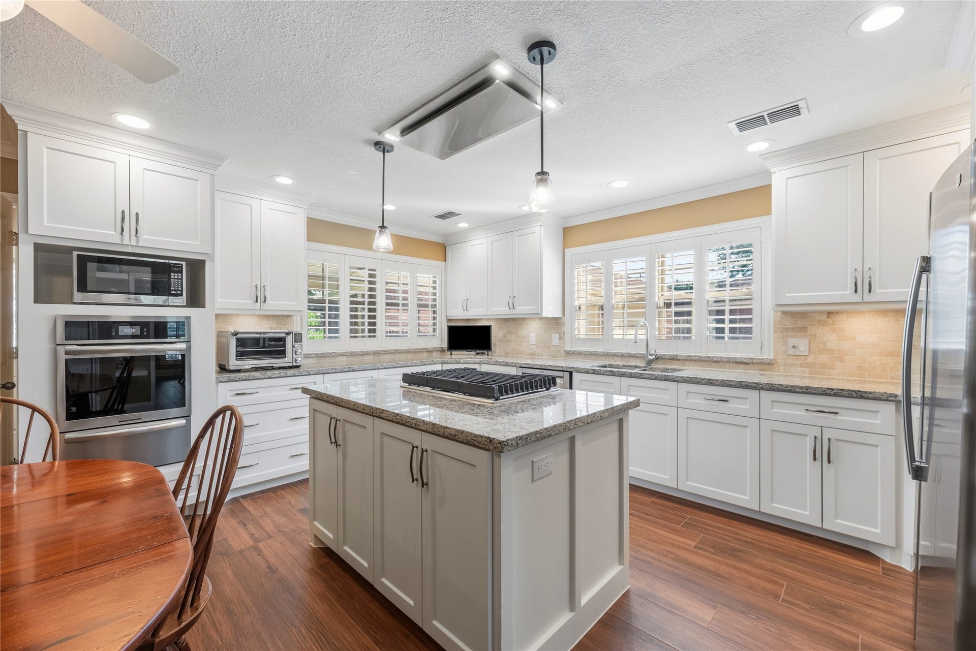 17906 Lone River Court, Houston, TX 77095 Gorgeous island kitchen features granite countertops, white cabinetry, under cabinet lighting, tile backsplash, stainless steel appliances and a gas cooktop.