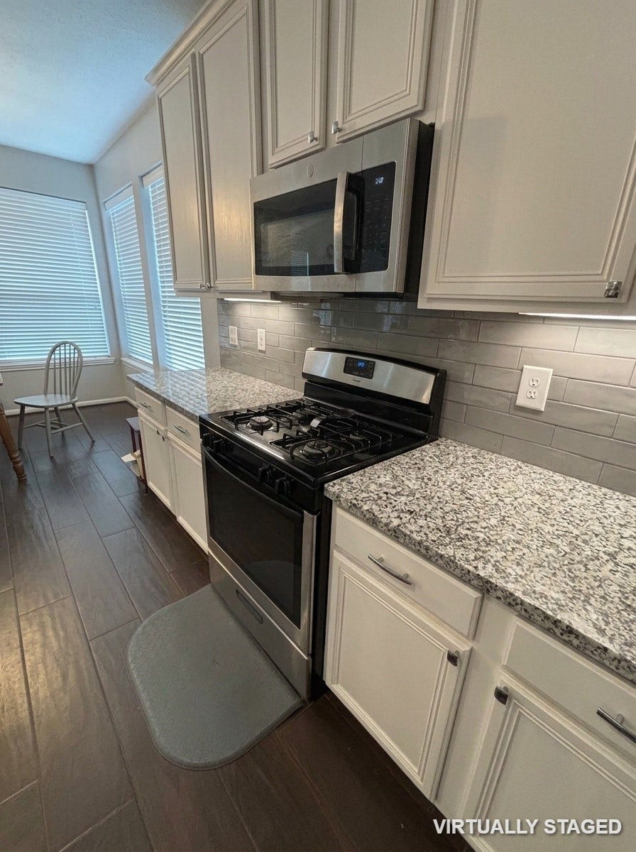 15806 Laurel Cove, Tomball, TX 77377 Spacious kitchen features granite island, custom white cabinetry, gas range and a sleek, modern backsplash