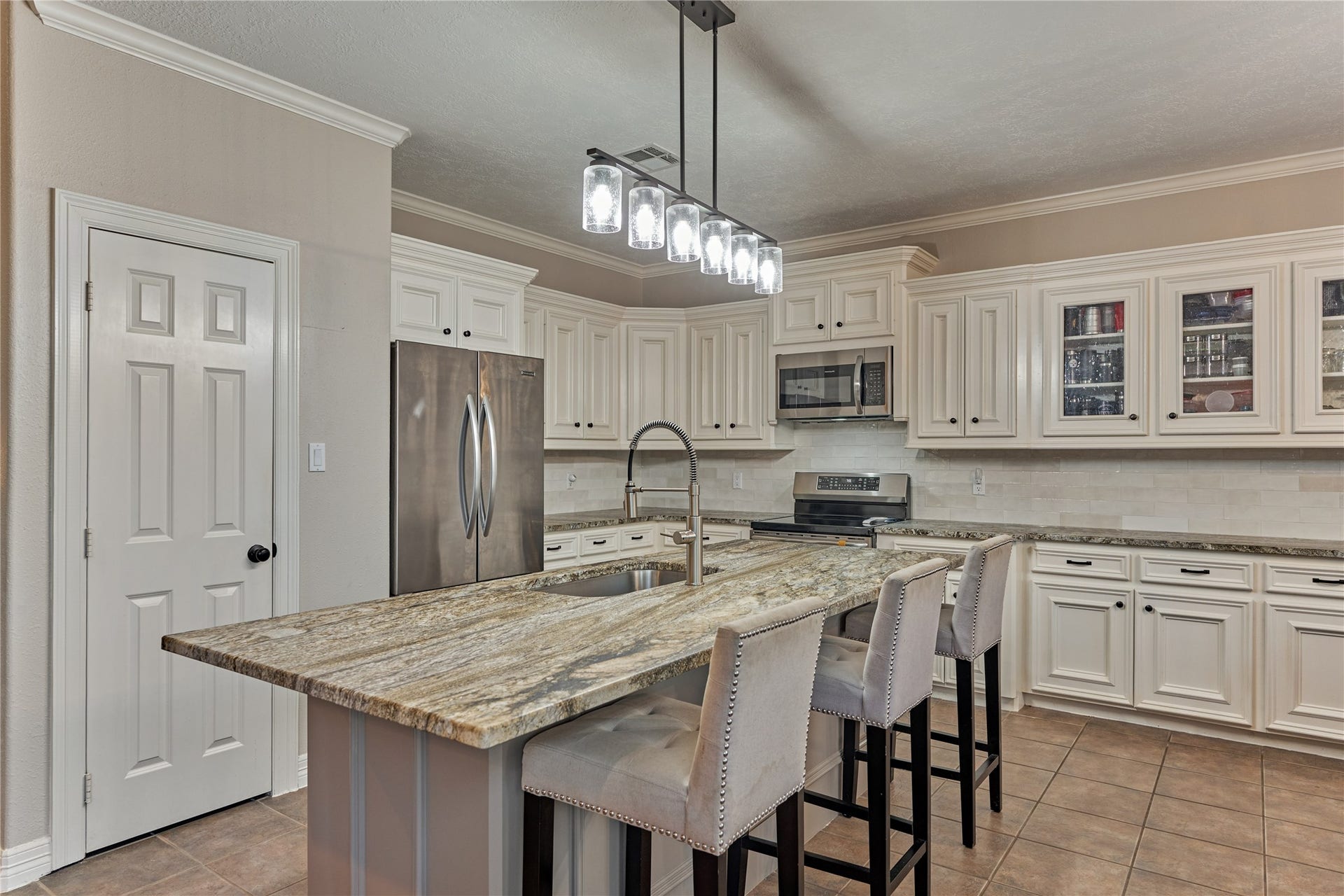 15 Newberry Court, Montgomery, TX 77356 Stylish lighting highlights the expansive breakfast bar, offering generous seating and a warm, inviting space for casual dining and entertaining.