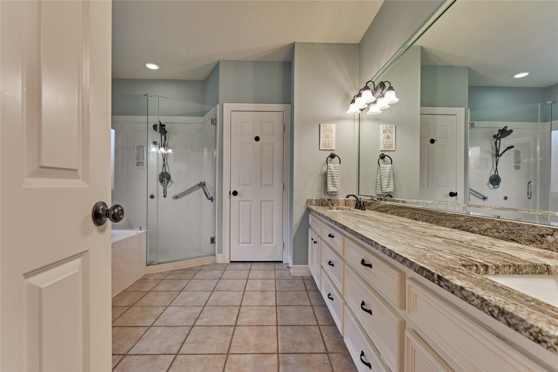 15 Newberry Court, Montgomery, TX 77356 Updated spa-inspired ensuite bath featuring dual vanities, granite countertops, a relaxing soaking tub, and a frameless walk-in shower.