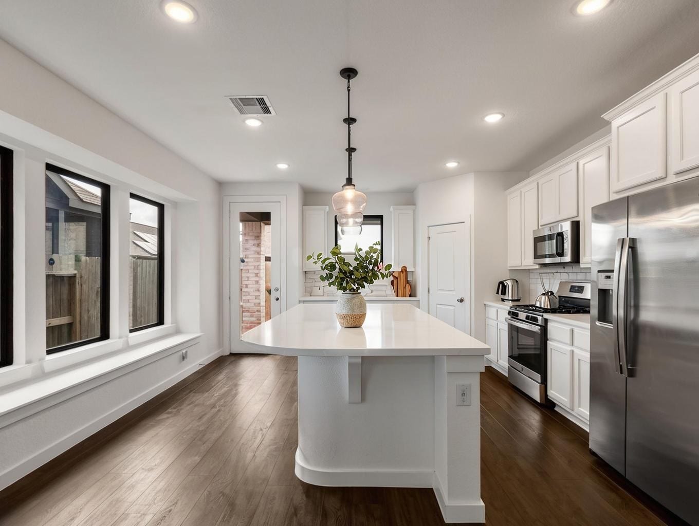 13021 Sapphire Lake Lane, La Marque, TX 77568 This kitchen angle showcases the island as the centerpiece of the home. Clean counters, warm flooring, and white cabinetry create a sharp, balanced look. Virtually staged.