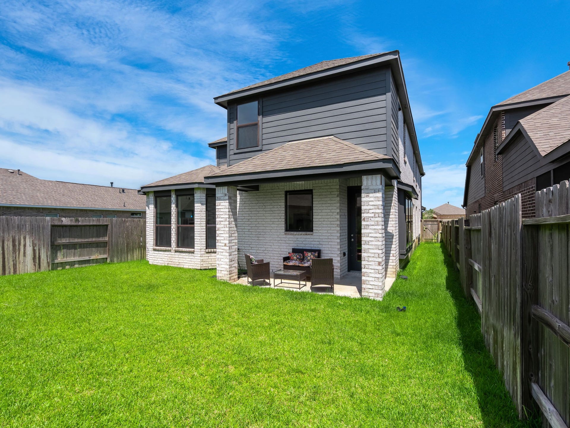 13021 Sapphire Lake Lane, La Marque, TX 77568 The backyard offers a fenced lawn with a covered patio and clean rear elevation. A quiet outdoor space with simple, usable appeal. Virtually staged.