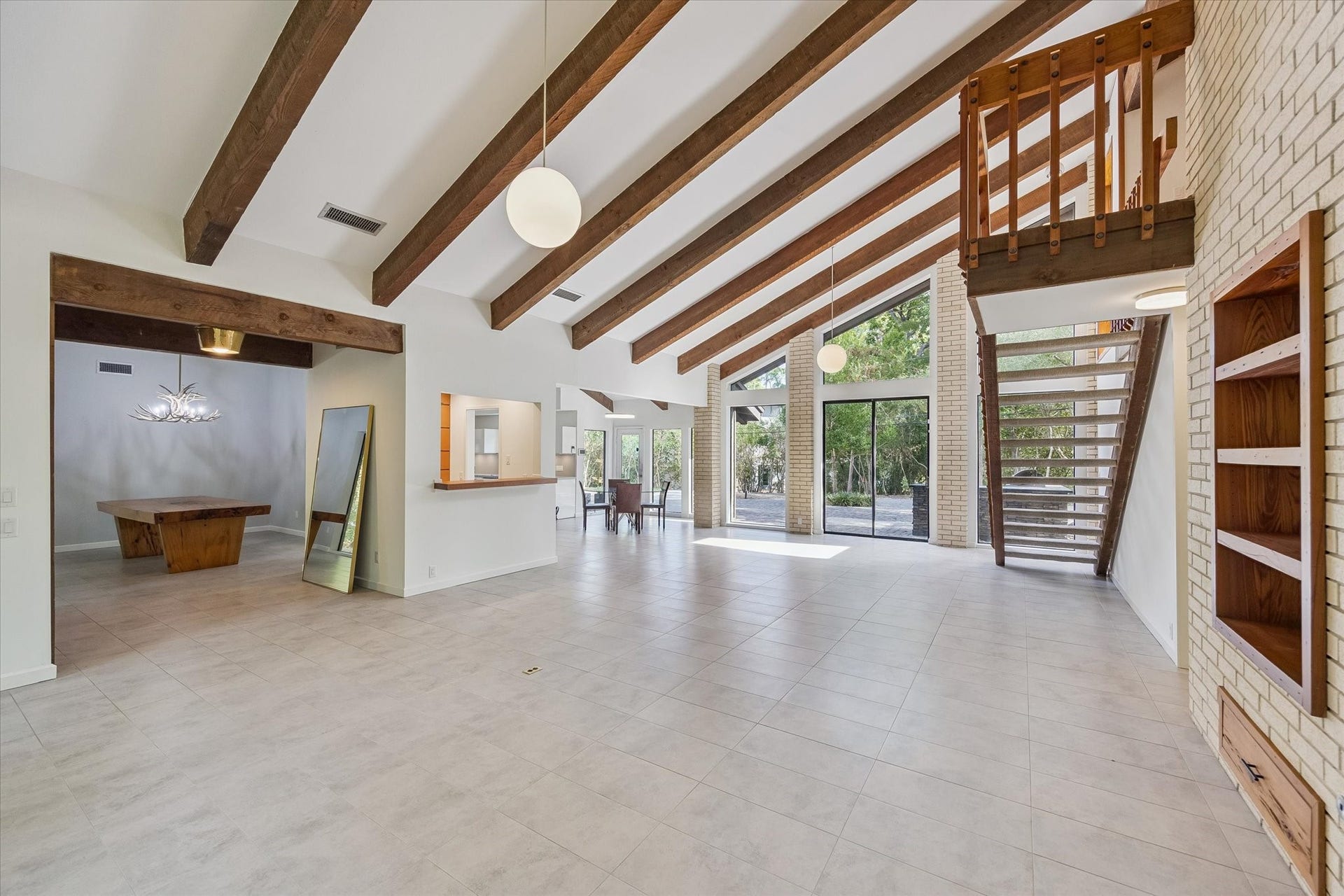 104 Gershwin Drive, Houston, TX 77079 Looking across the living room reveals the homes easy flow to the dining room & kitchen, while soaring ceilings, exposed beams & expansive windows carry the architectural character throughout.